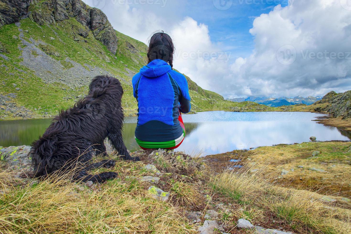 Girl looks scene in the mountains with his dog photo