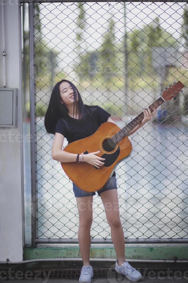 adolescente asiático tocando la guitarra española con emoción de felicidad foto