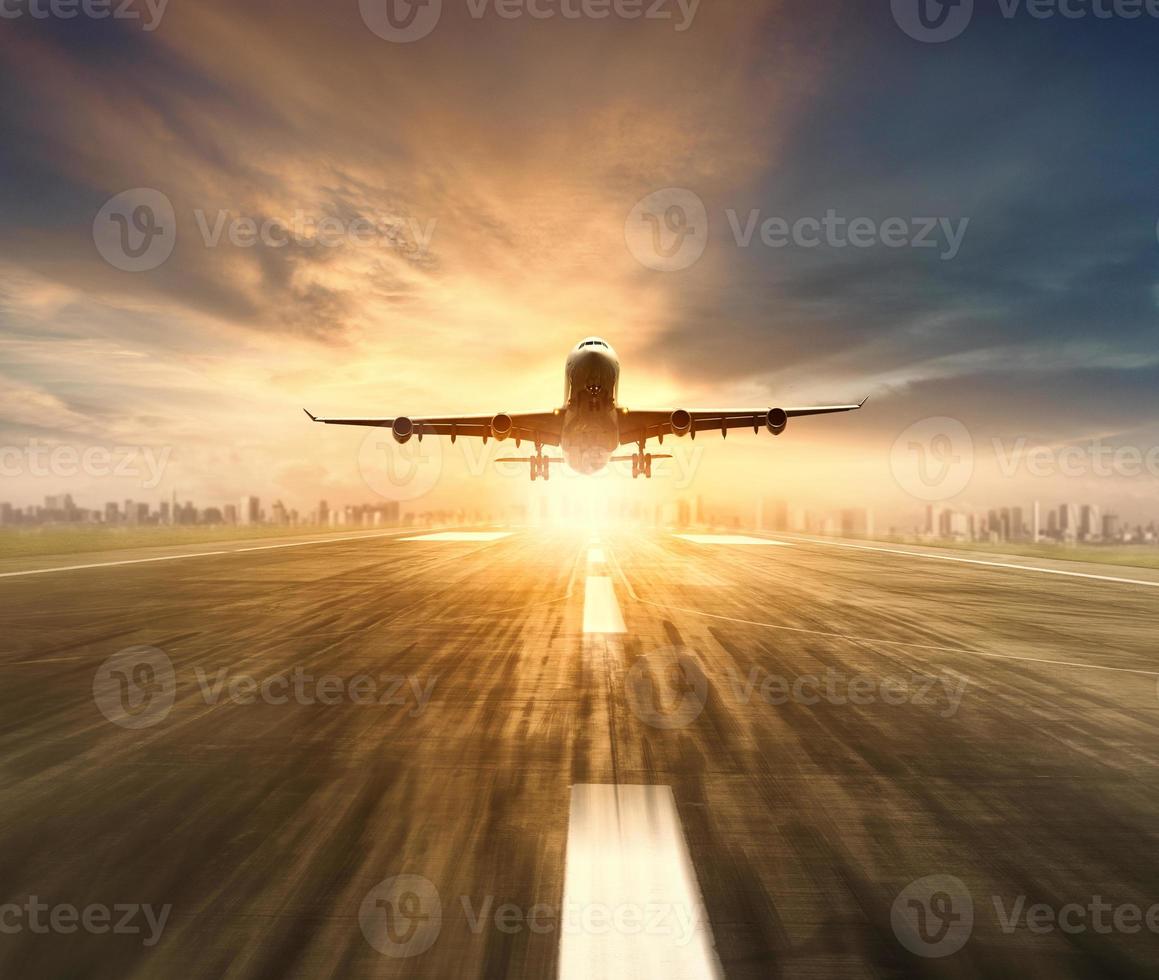 air plane flying over airport runway with city scape and sunset sky background photo