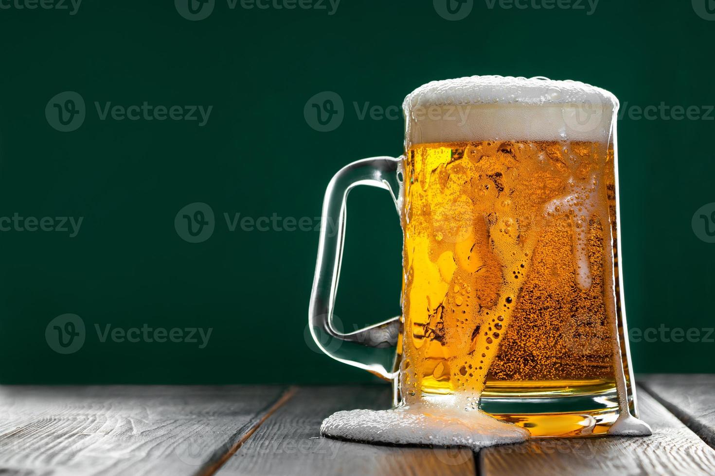 Beer is poured out of glass. Mug with traditional Irish ale on a dark background. photo