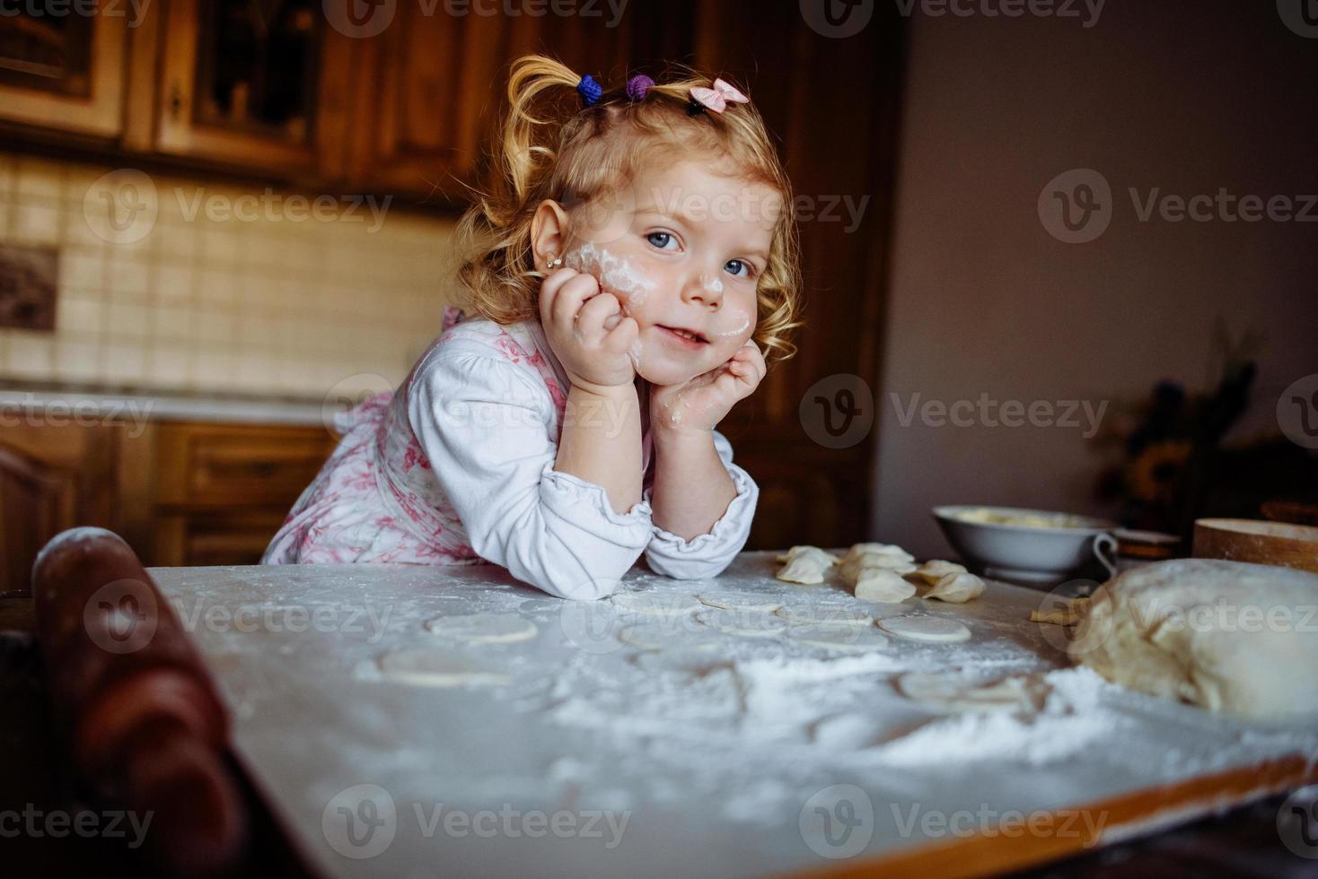 baker girl in chef hat at kitchen photo