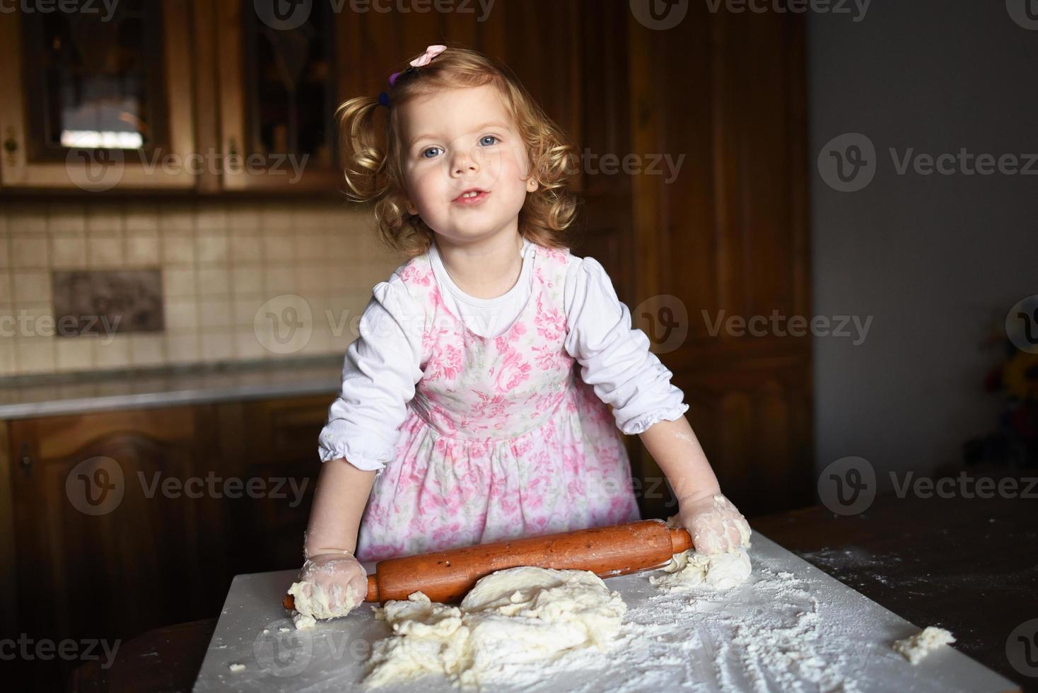 niña sonriente amasando la masa foto