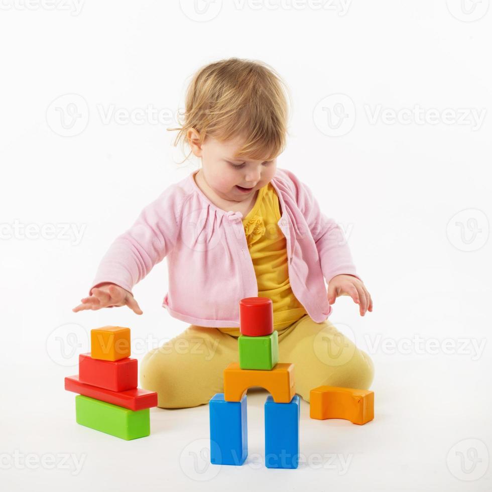 little girl playing with colorful toy blocks photo