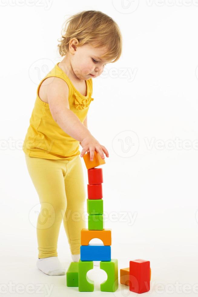 little girl playing with colorful toy blocks photo