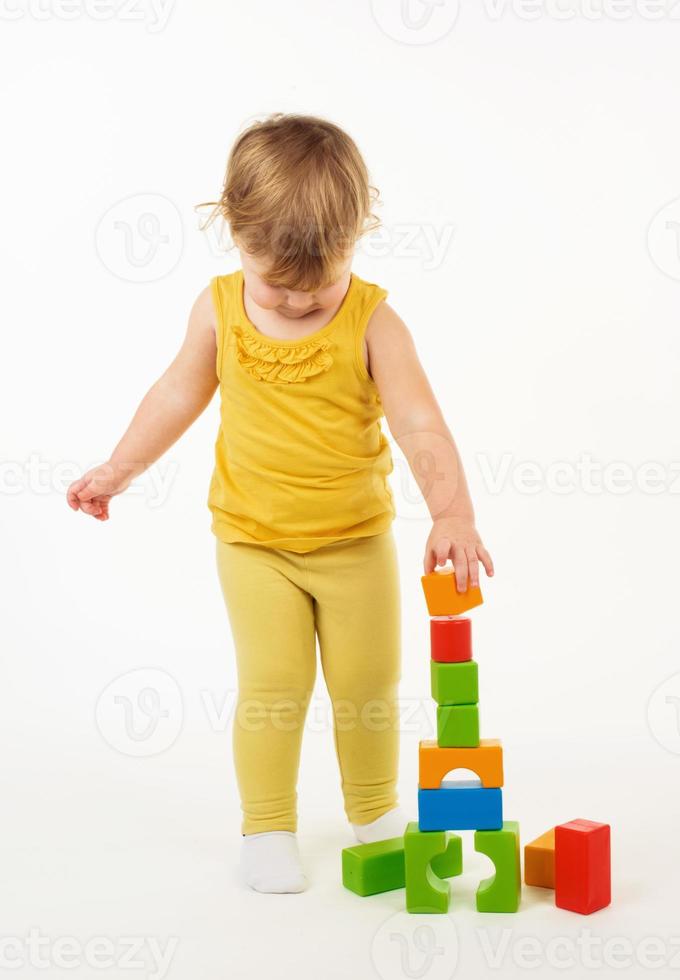 little girl playing with colorful toy blocks photo