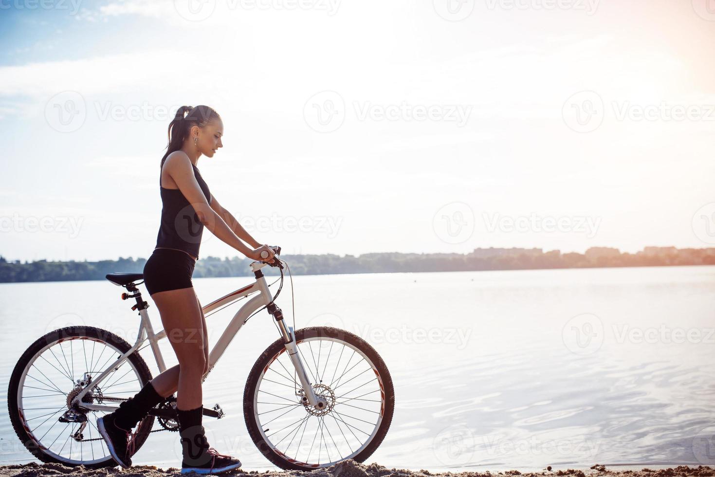 woman on a bicycle near the water photo