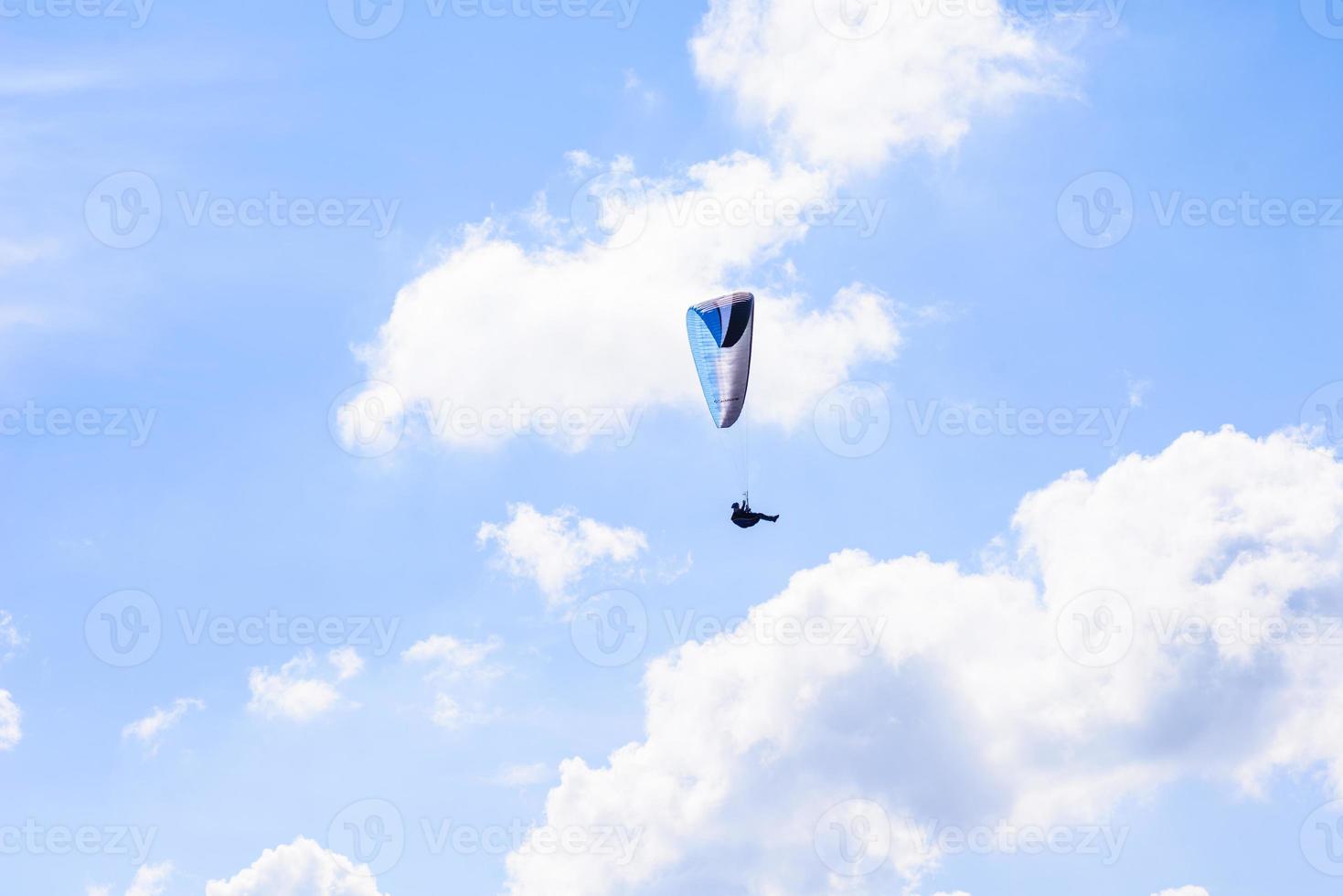 hombre en un paracaídas volando en el cielo despejado foto