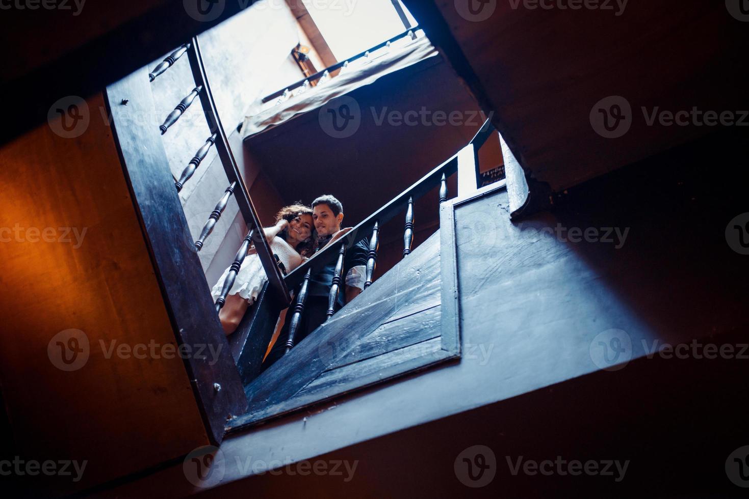 Fashionable young couple standing on stairs and hugging each other photo