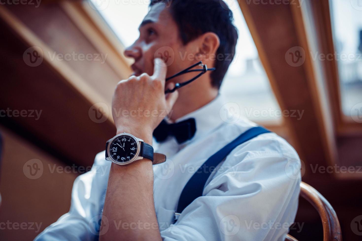 Elegant young man in suspenders and glasses in cafe photo