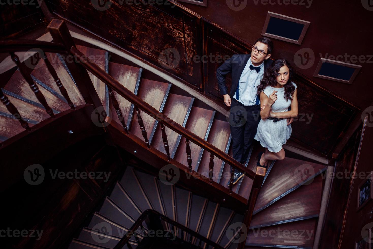 Fashionable young couple standing on stairs and hugging each other photo