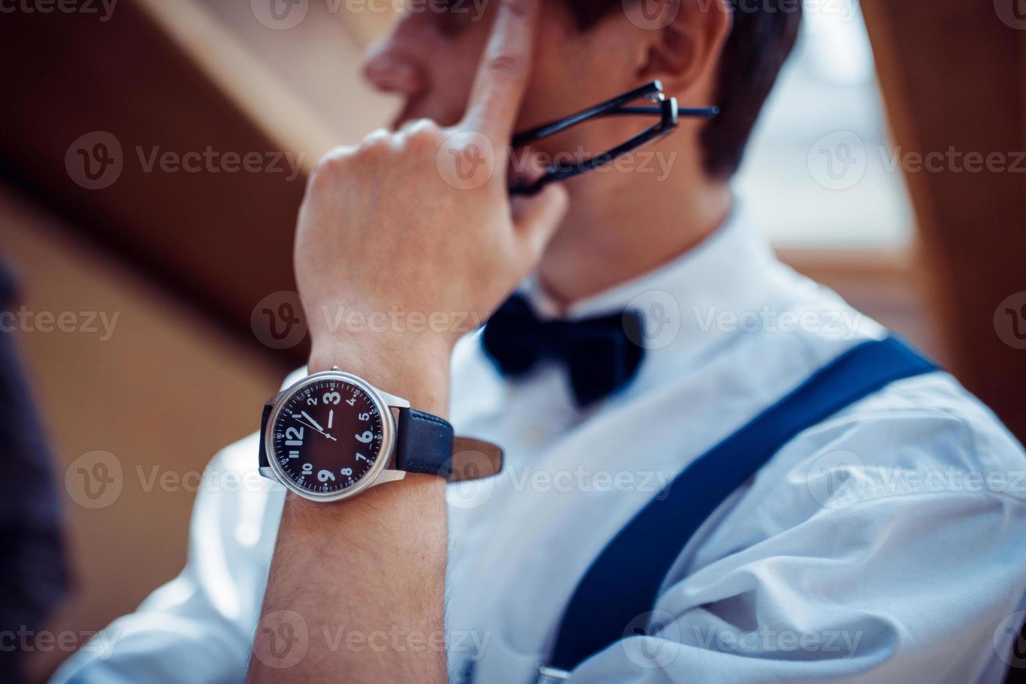 Elegant young man in suspenders and glasses in cafe photo