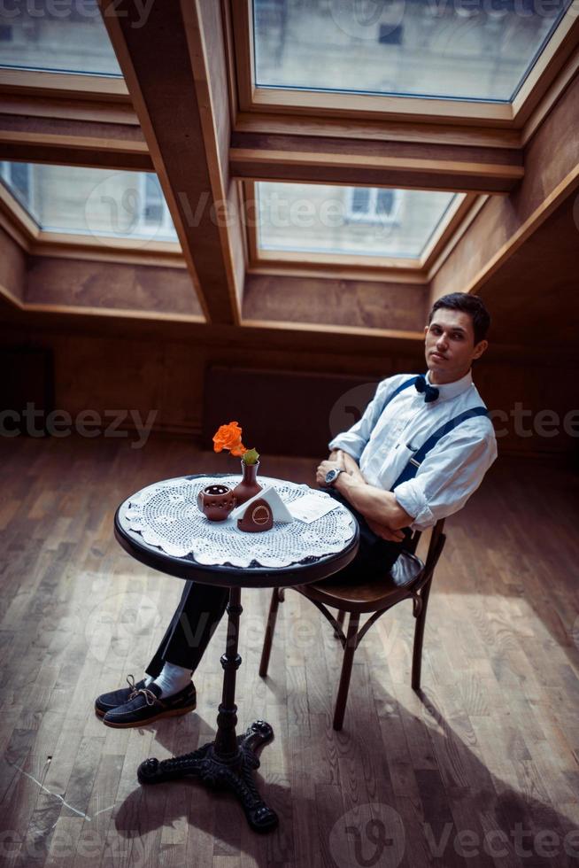 Elegant young man in suspenders and glasses in cafe photo