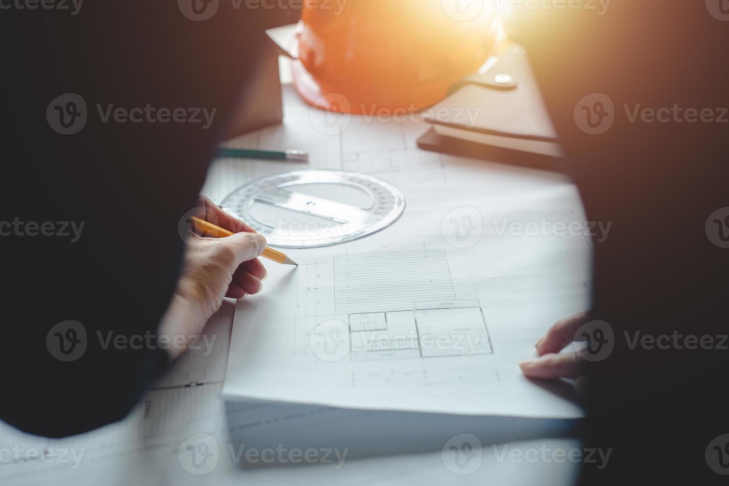 manos de arquitecto o ingeniero usando brújula de dibujo con plano en el escritorio en la oficina. equipo de arquitectos ingenieros discutiendo y verificando documentos y flujo de trabajo empresarial. concepto de construcción. foto