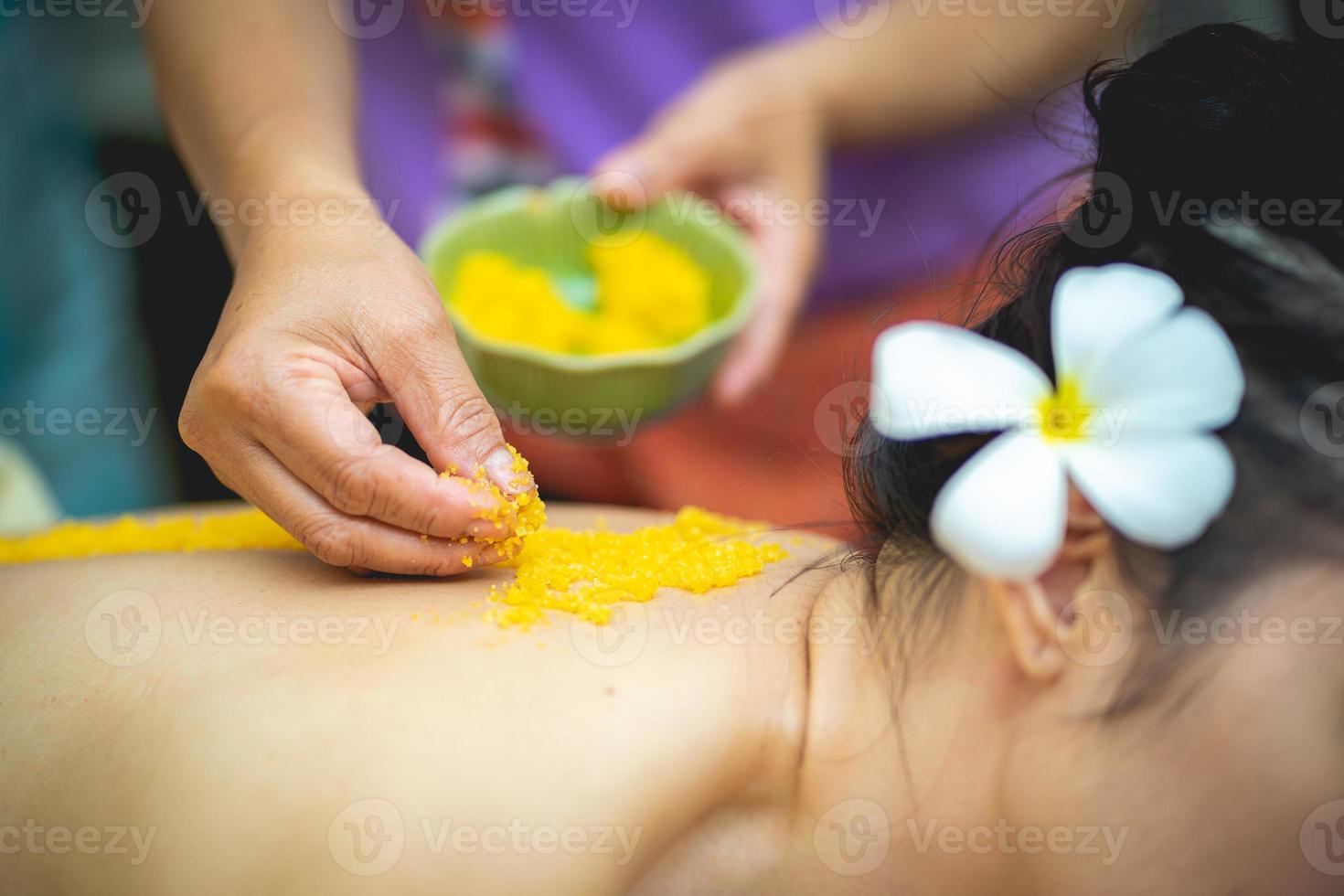 Beautiful woman njoying a salt scrub massage and having exfoliation treatment in spa room. Brunette getting a salt scrub beauty treatment in the health spa. Body Scrub. photo