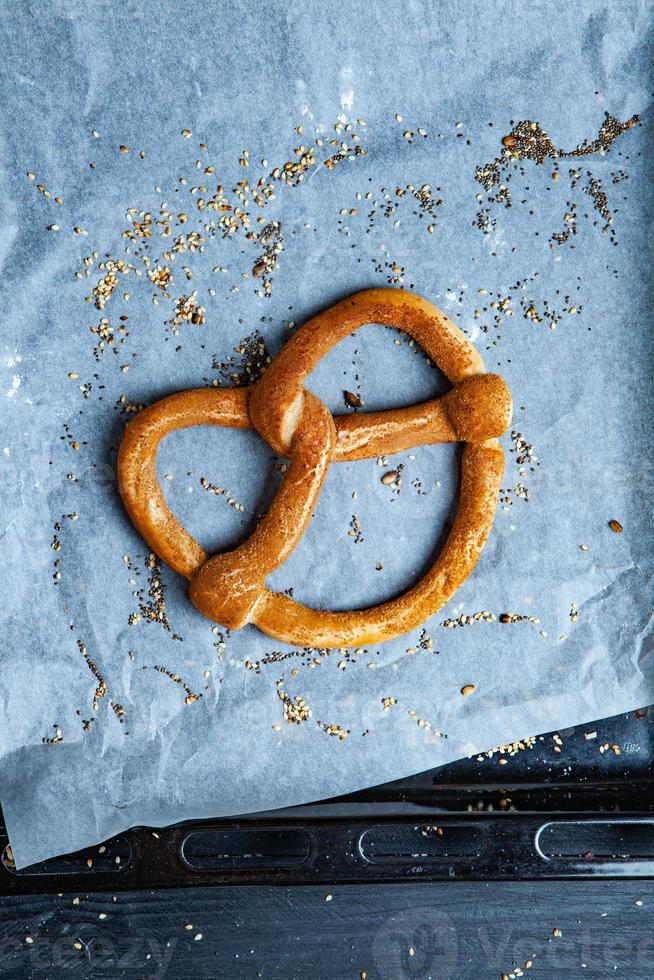 pretzels suaves caseros recién preparados. diferentes tipos de panecillos horneados con semillas sobre un fondo negro. foto