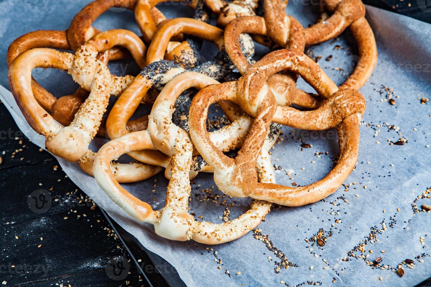 Fresh prepared homemade soft pretzels. Different types of baked bagels with seeds on a black background. photo