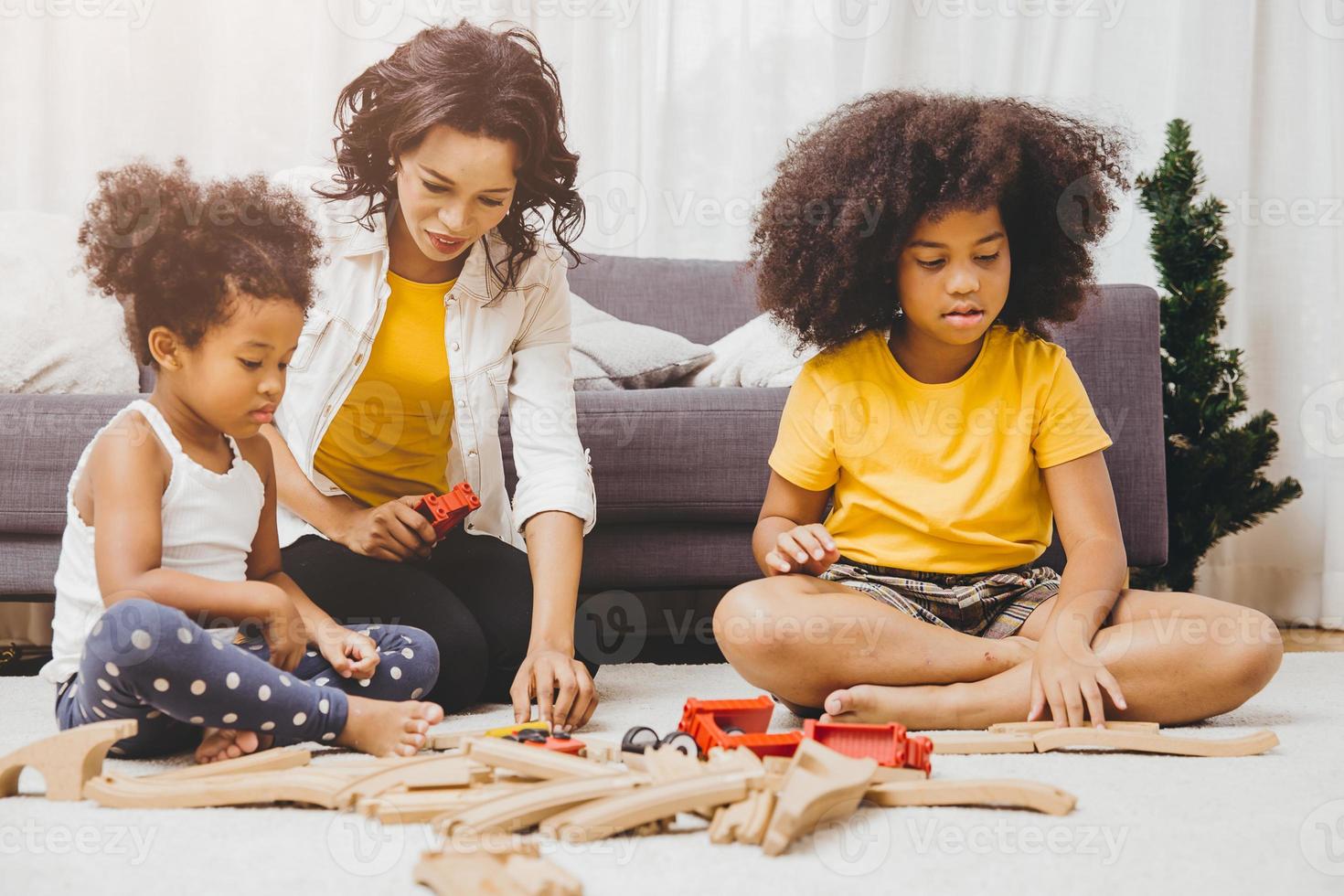 Single mom living with two daughter learning and playing puzzle toy in home apartment. Nanny looking or childcare at living room black people. photo