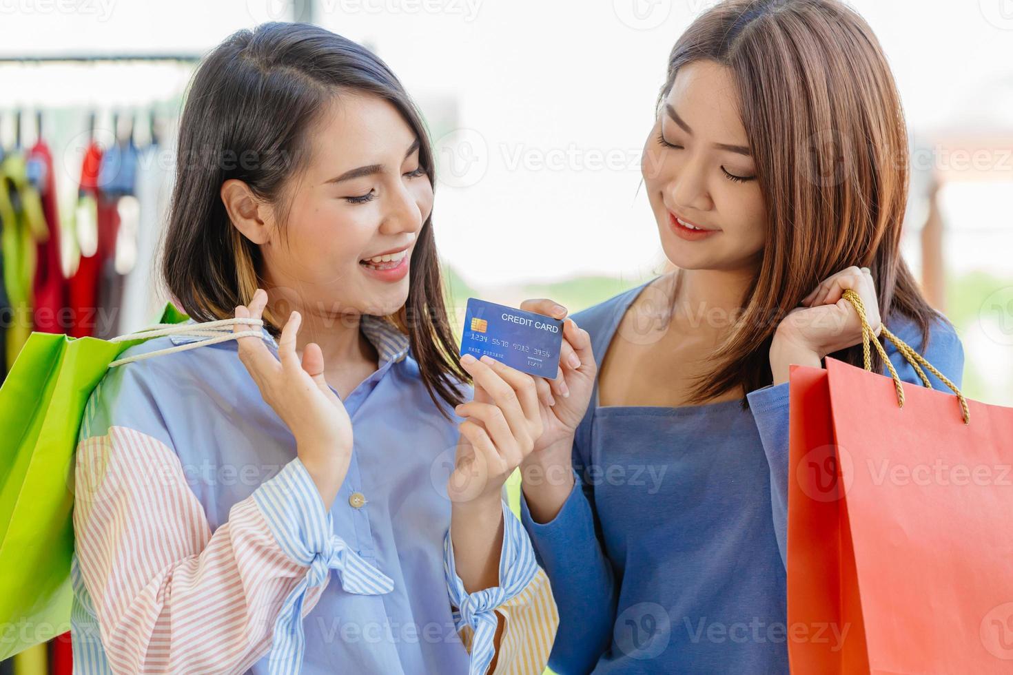 Asian girls enjoy shopping with cashless credit card payment with friend happy moment fun in sale shop together. photo