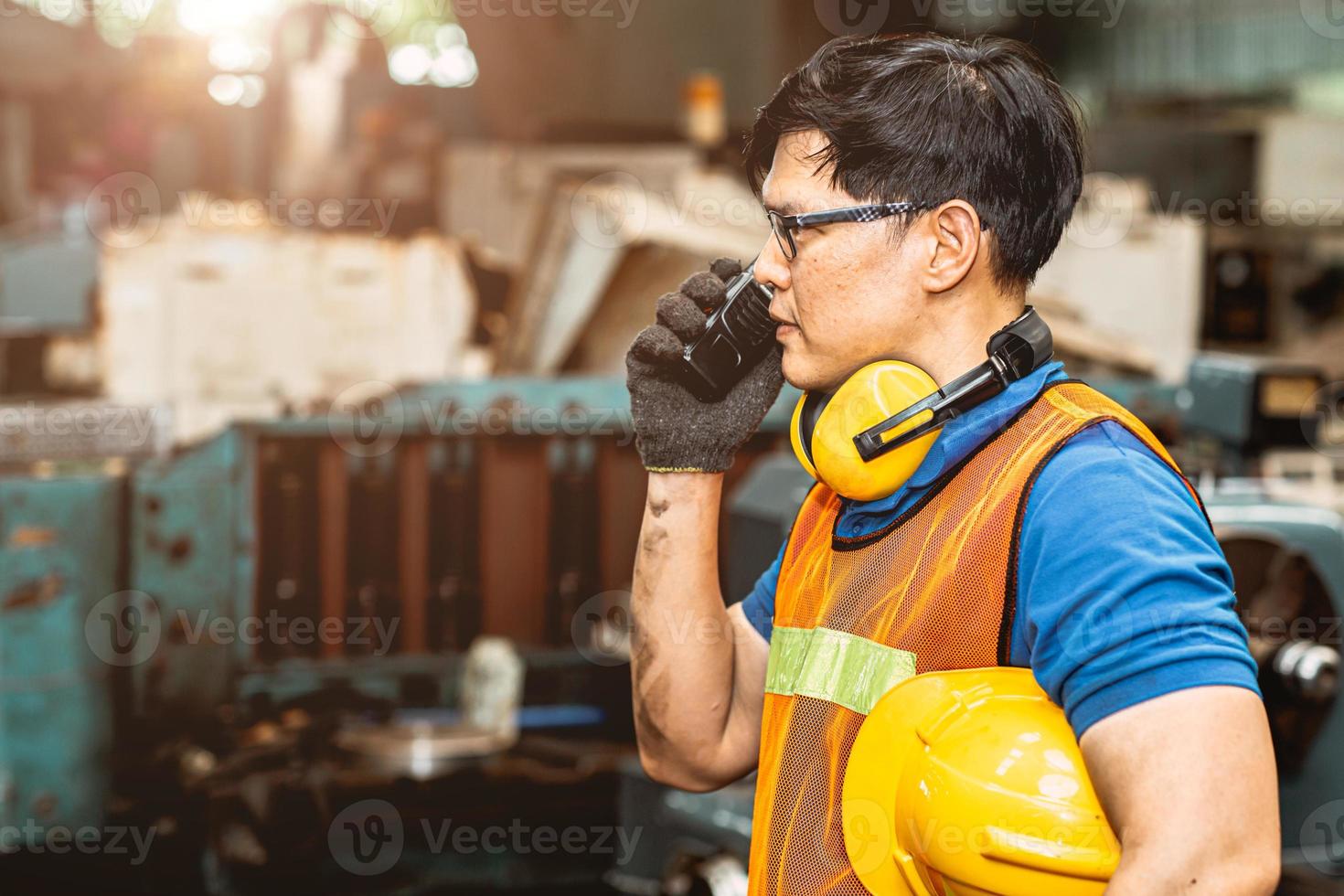 Asian engineer worker with protection suit set hard working in factory handle communication radio looking camera and smile. photo