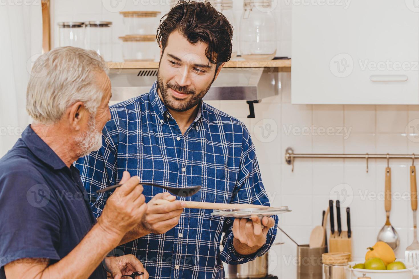 los ancianos prueban la comida mientras cocinan en la cocina con un joven de la familia para quedarse juntos en casa. foto