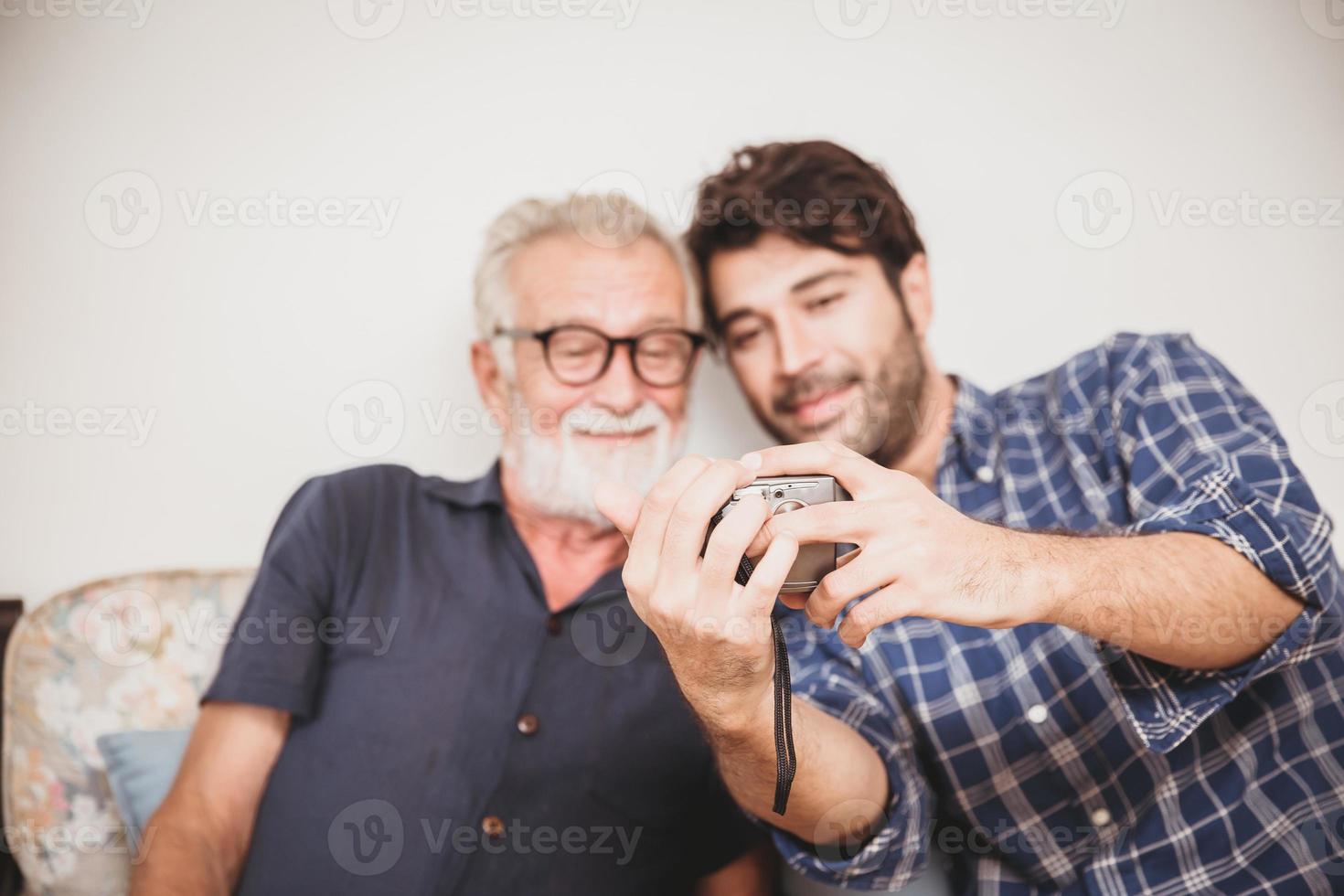 Elder looking replay photos from digital camera with his son happiness family moment with digital device concept.