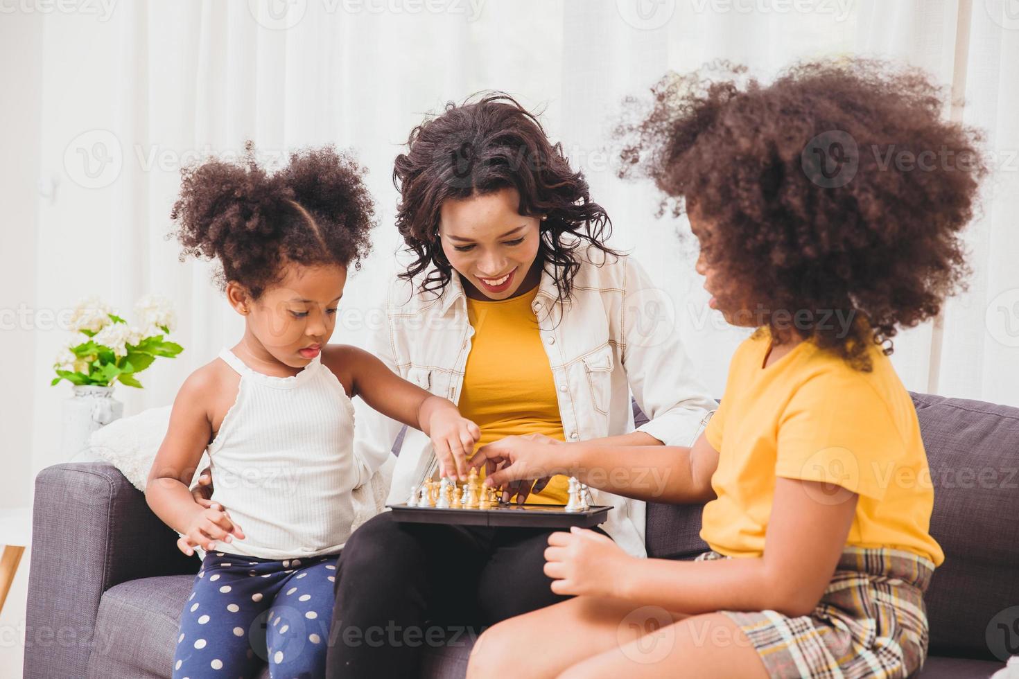 buena madre inteligente, enseñando a sus hijos a ser genios y niñas inteligentes aprendiendo a jugar ajedrez en vacaciones en casa. foto