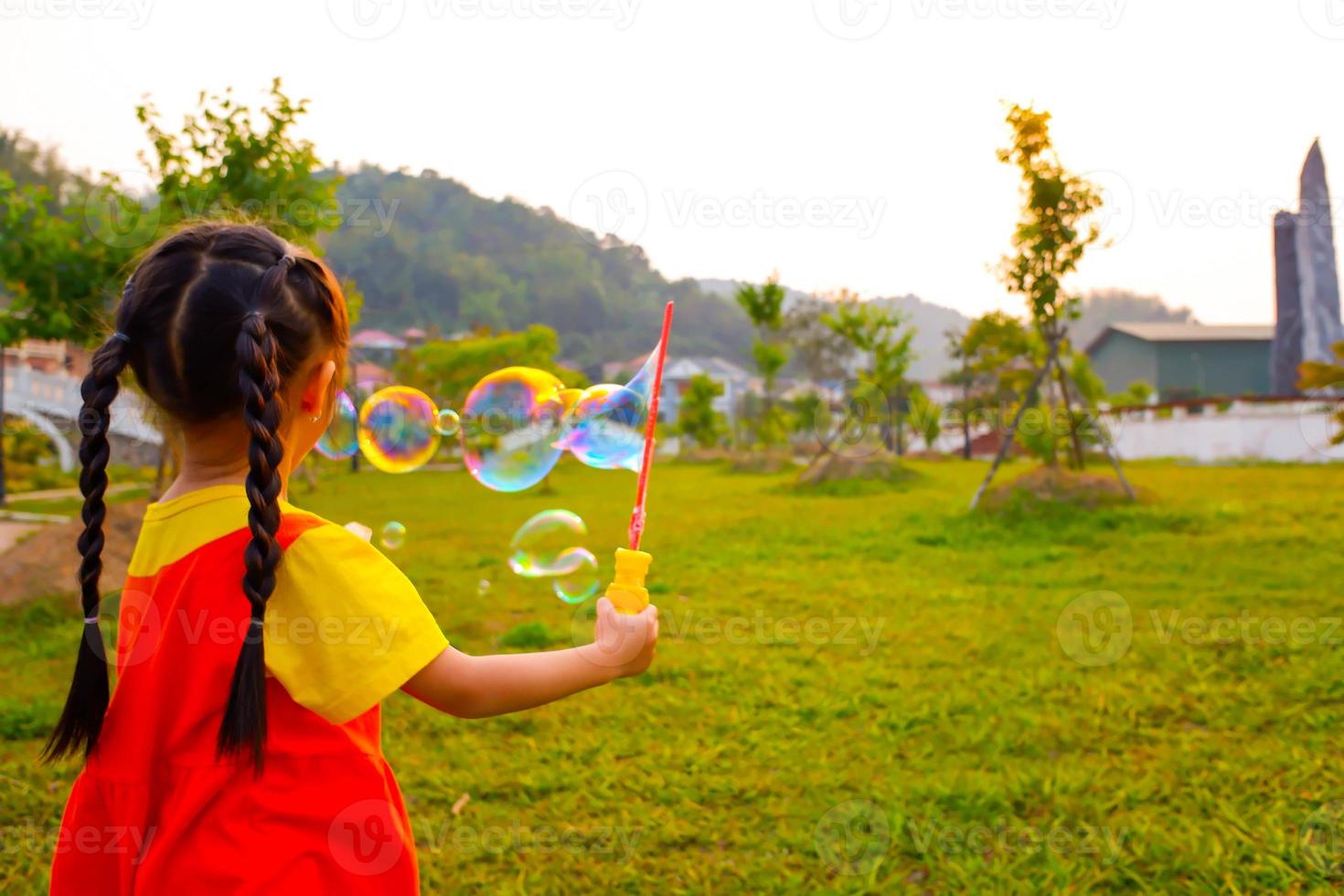 Lovely Baby girl wears yellow-orange outfit, gokowa outfit or Mugunghwa playing bubble in a public park. Girls and teen fashion dress. photo