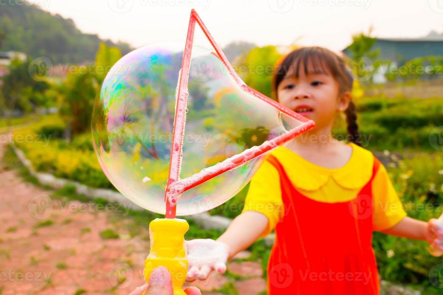 la encantadora niña viste un traje amarillo-naranja, un traje de gokowa o un mugunghwa jugando a la burbuja en un parque público. vestido de moda para niñas y adolescentes. foto
