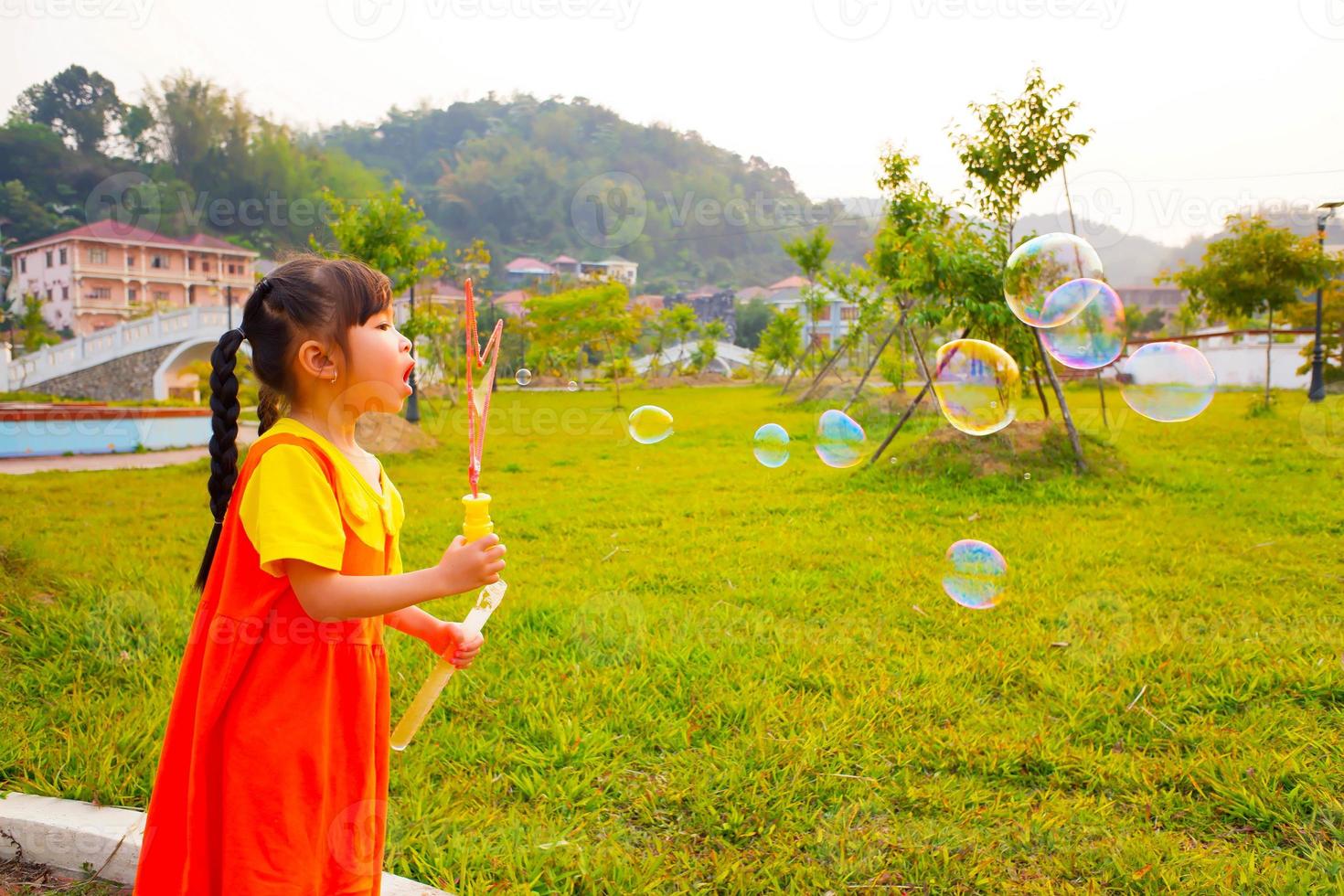 Lovely Baby girl wears yellow-orange outfit, gokowa outfit or Mugunghwa playing bubble in a public park. Girls and teen fashion dress. photo