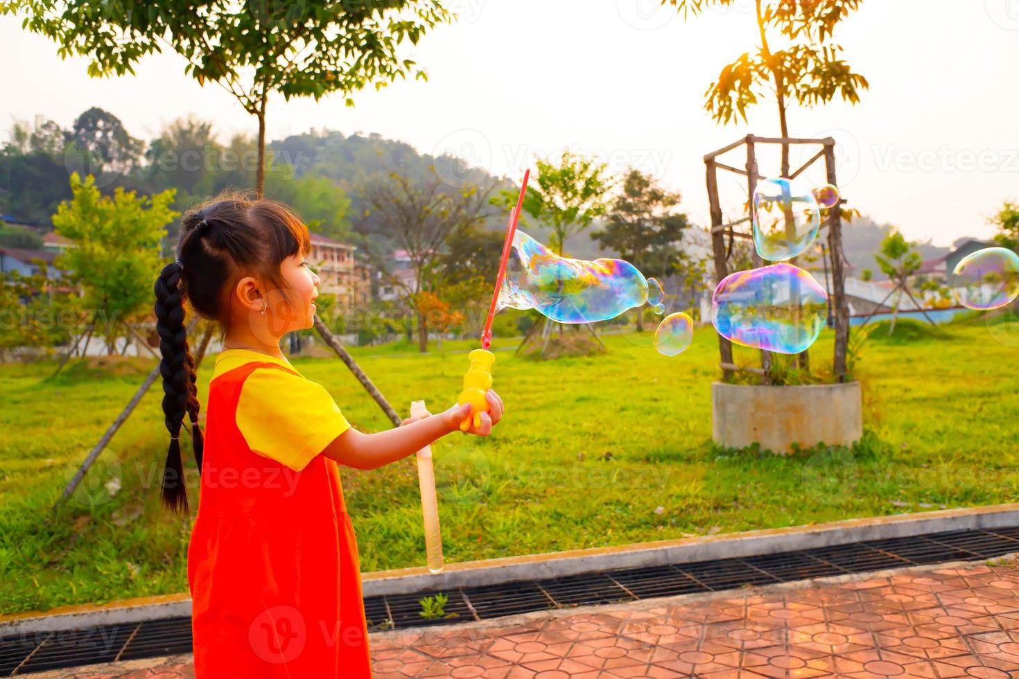 Lovely Baby girl wears yellow-orange outfit, gokowa outfit or Mugunghwa playing bubble in a public park. Girls and teen fashion dress. photo