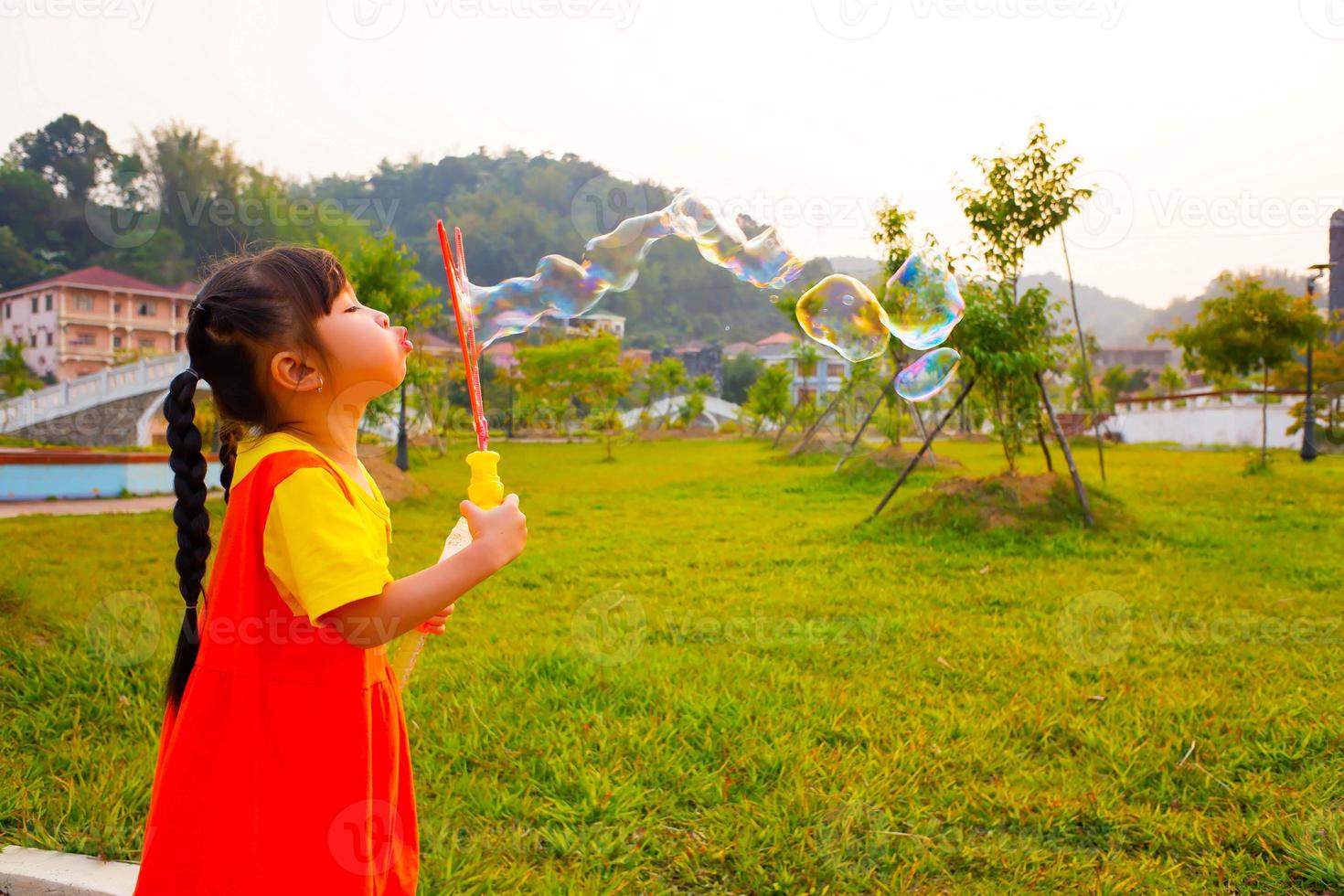 Lovely Baby girl wears yellow-orange outfit, gokowa outfit or Mugunghwa playing bubble in a public park. Girls and teen fashion dress. photo