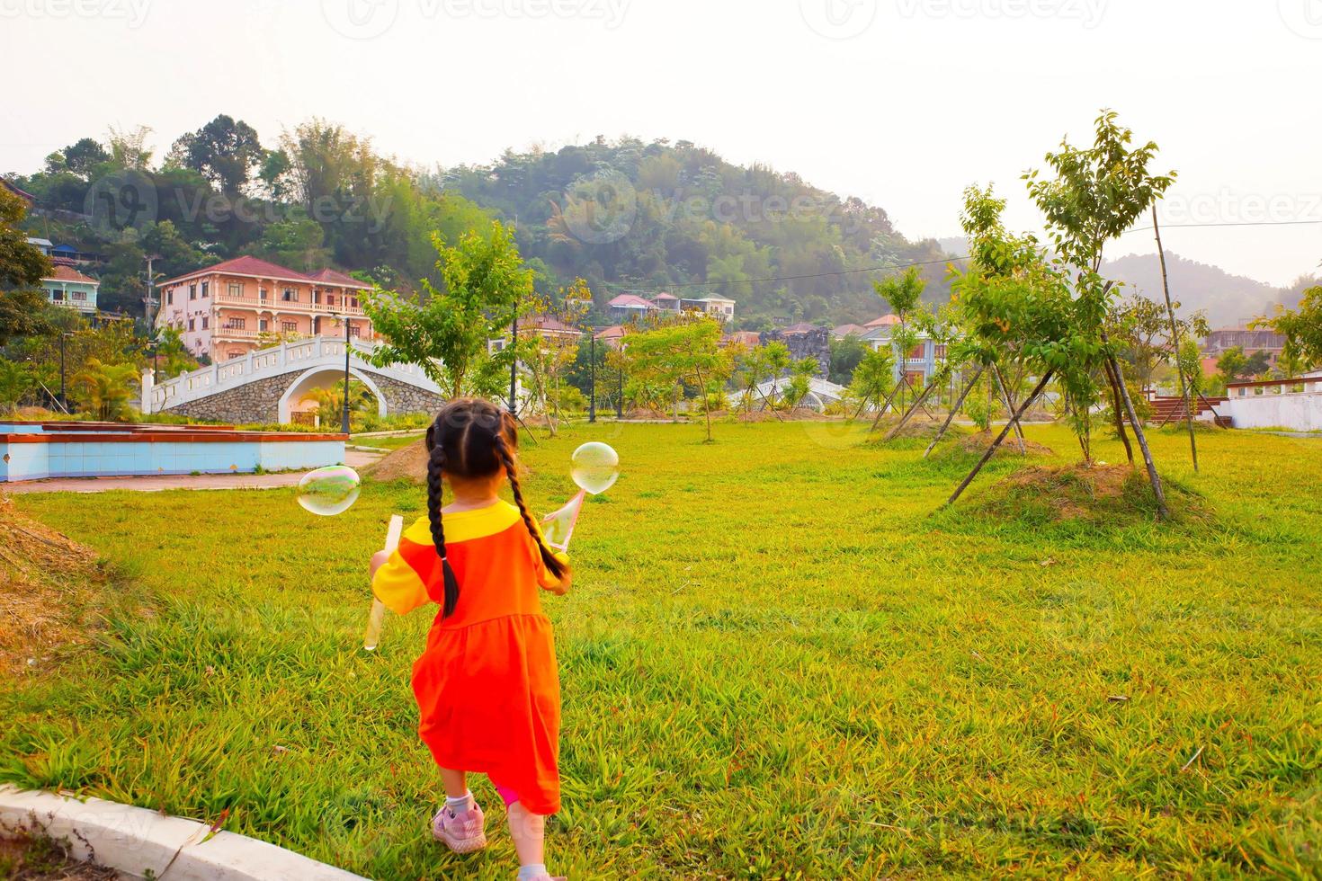 Lovely Baby girl wears yellow-orange outfit, gokowa outfit or Mugunghwa playing bubble in a public park. Girls and teen fashion dress. photo