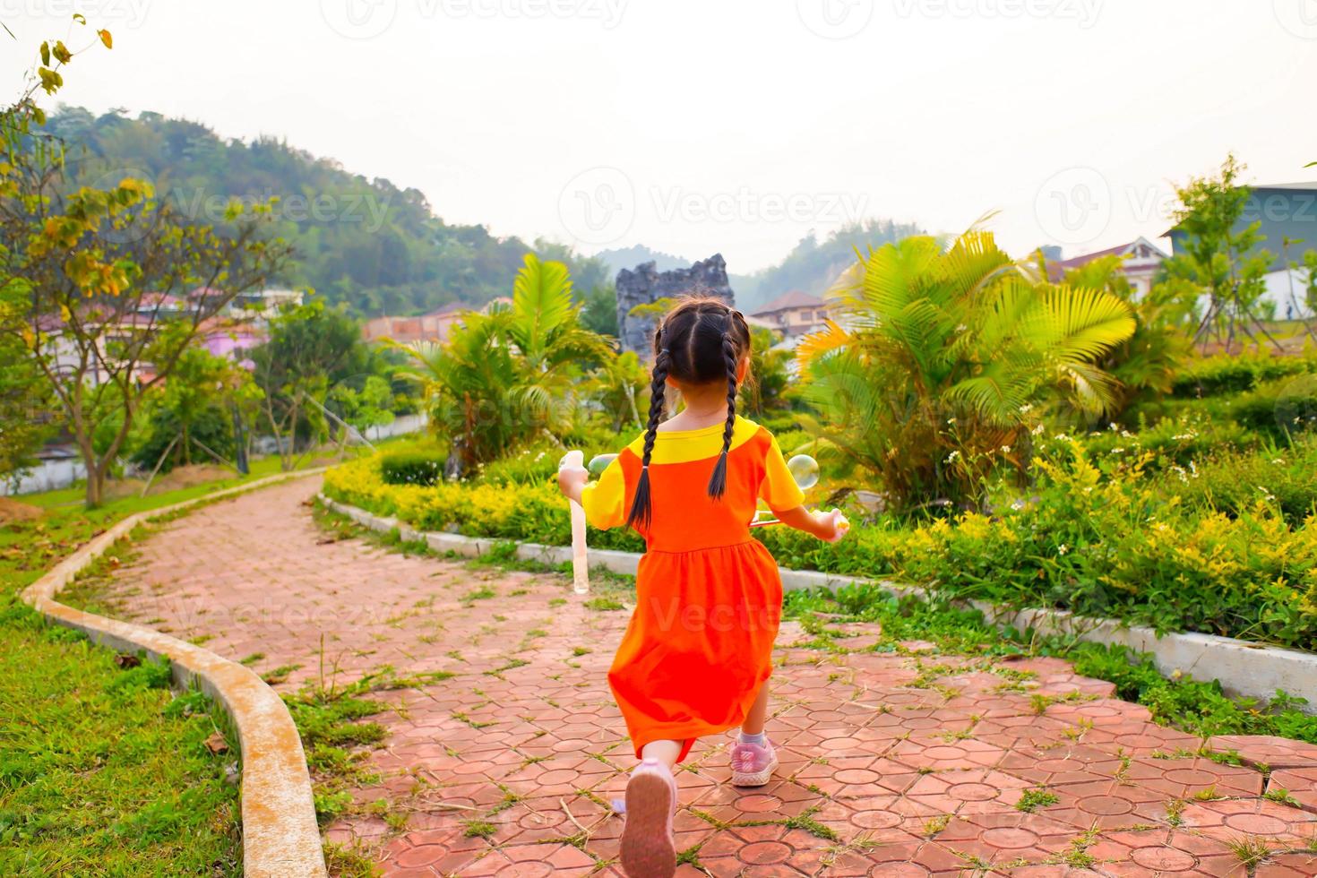 Lovely Baby girl wears yellow-orange outfit, gokowa outfit or Mugunghwa playing bubble in a public park. Girls and teen fashion dress. photo
