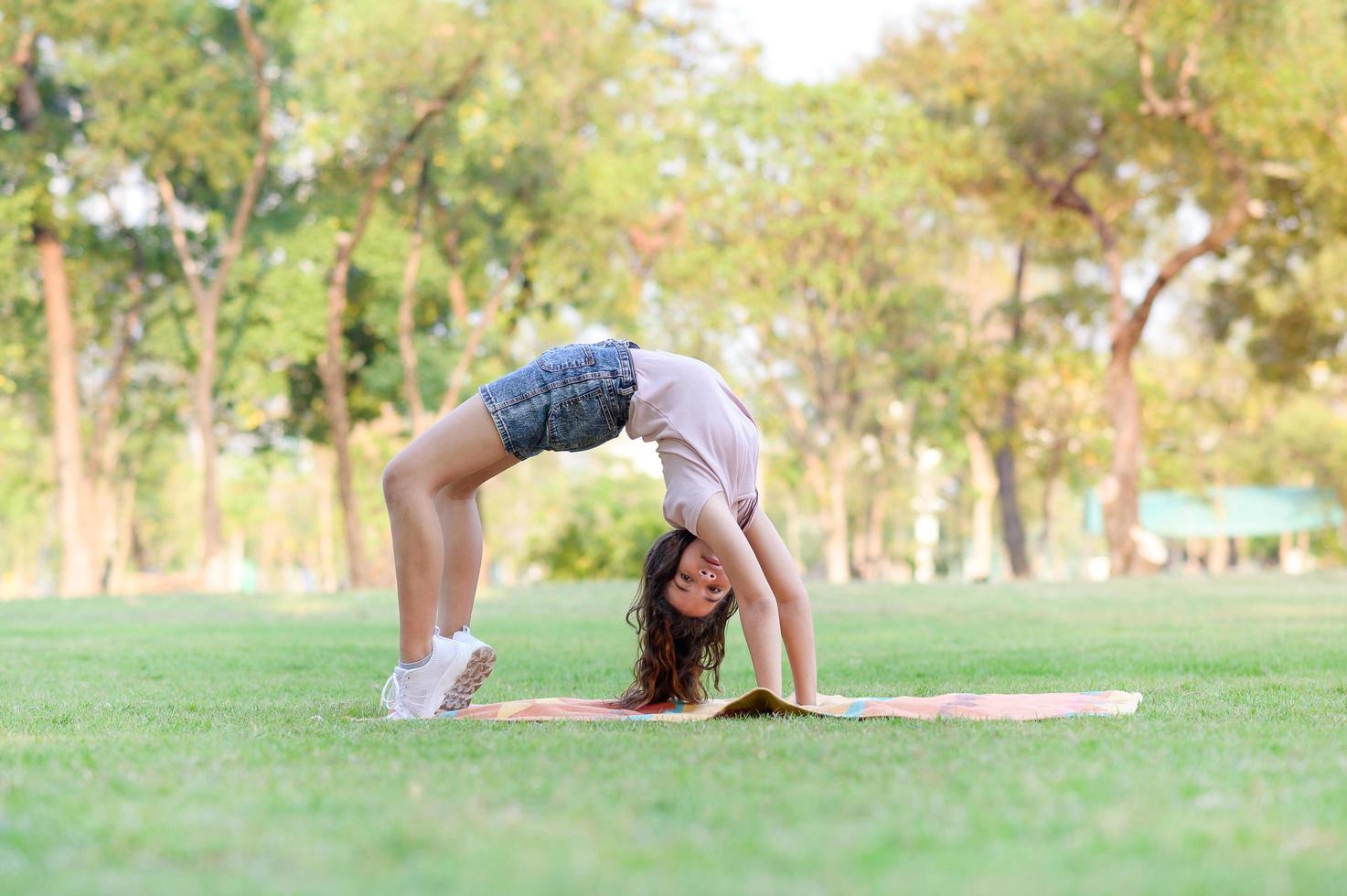 niñas medio tailandesas-europeas haciendo gimnasia como parte de su aprendizaje fuera de la escuela en el parque foto