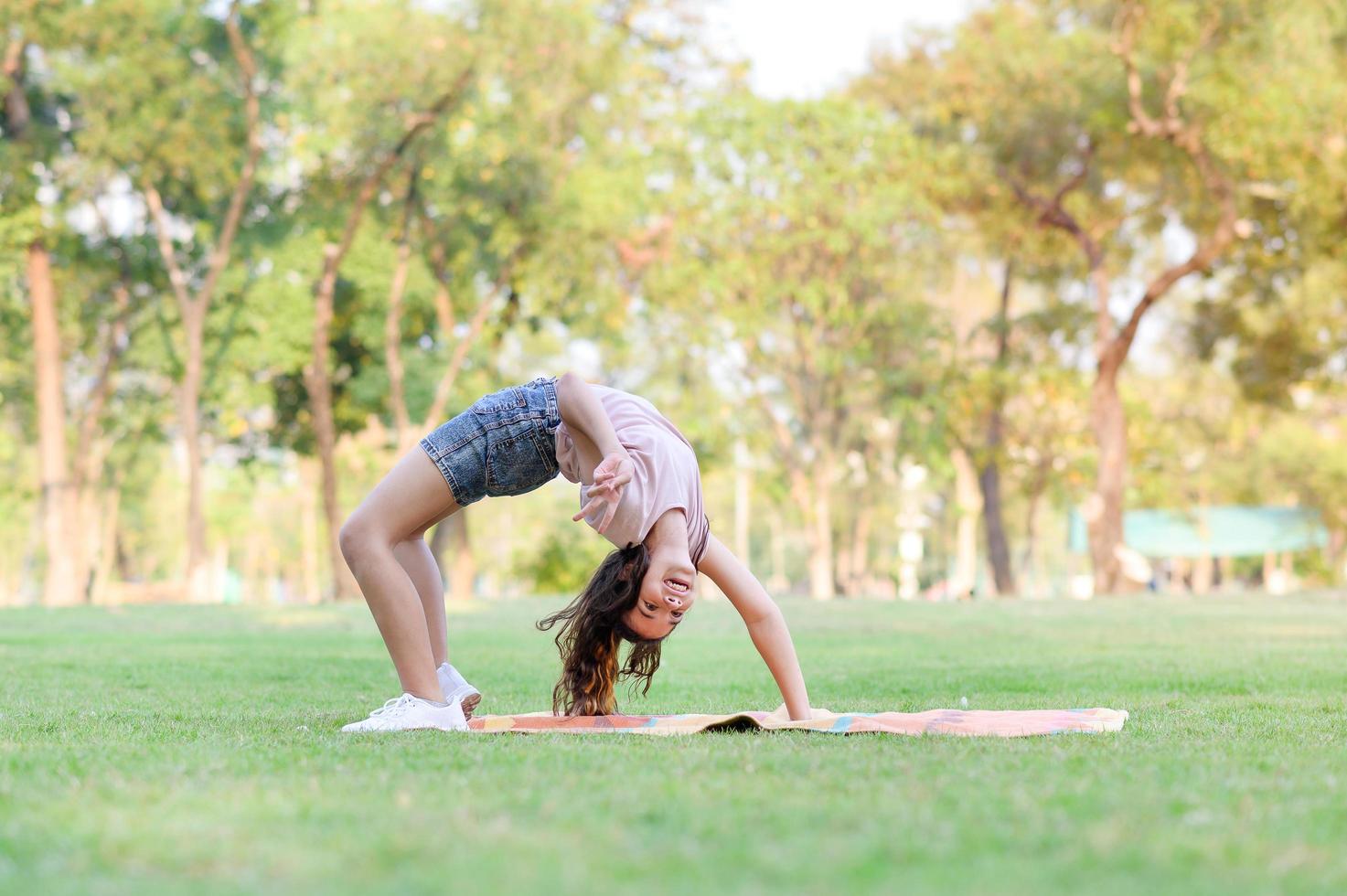 niñas medio tailandesas-europeas haciendo gimnasia como parte de su aprendizaje fuera de la escuela en el parque foto