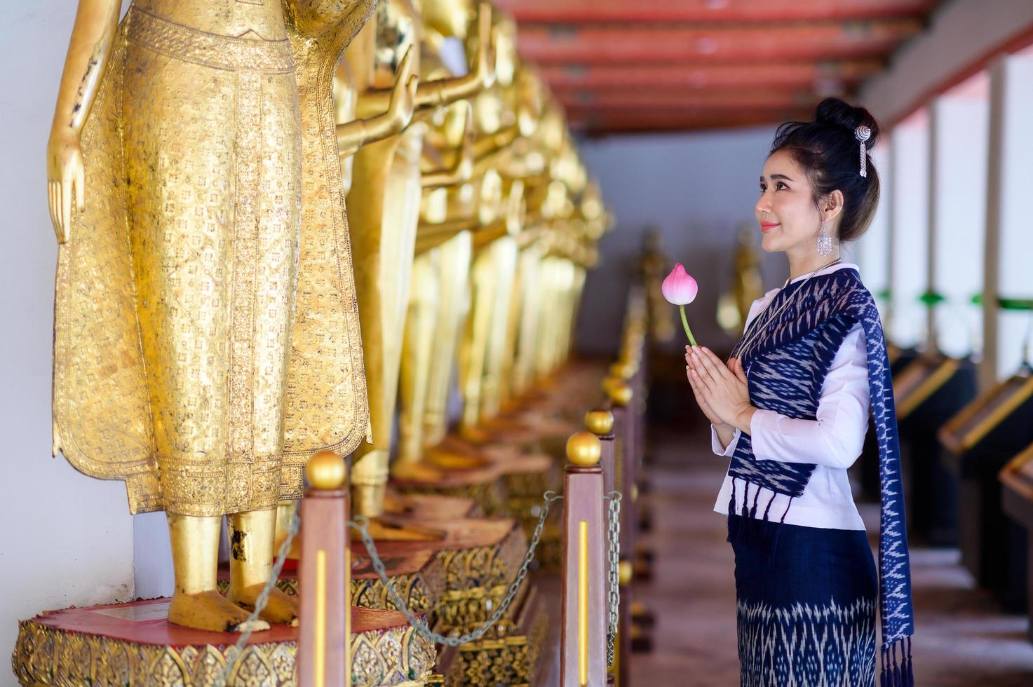 atractiva mujer tailandesa con un antiguo vestido tailandés sostiene flores frescas que rinden homenaje a buda para pedir un deseo en el festival tradicional de songkran en tailandia foto