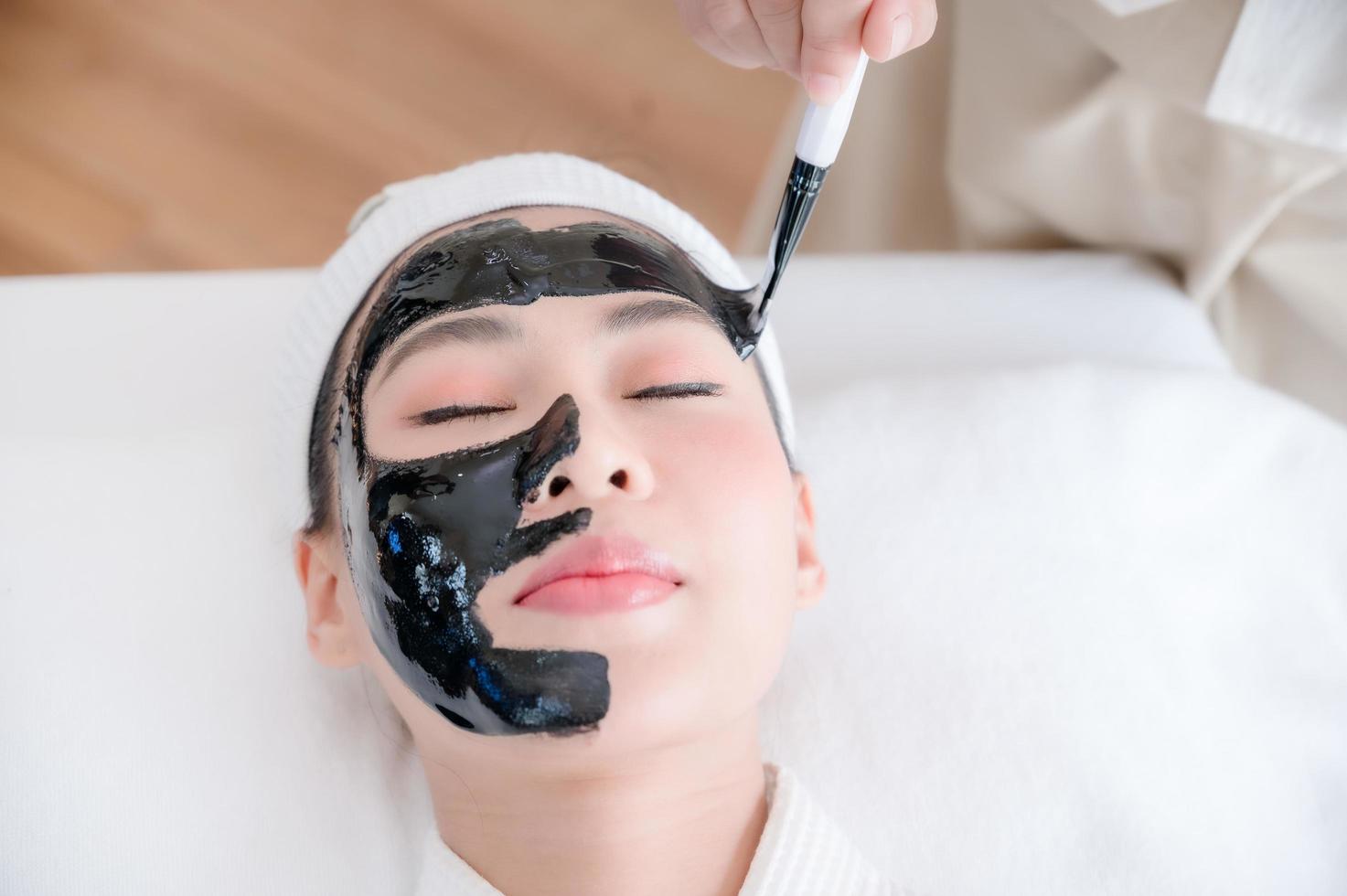 Professional masseuses in spa salons use spa mud brushes to give Asian beauties facial treatments photo