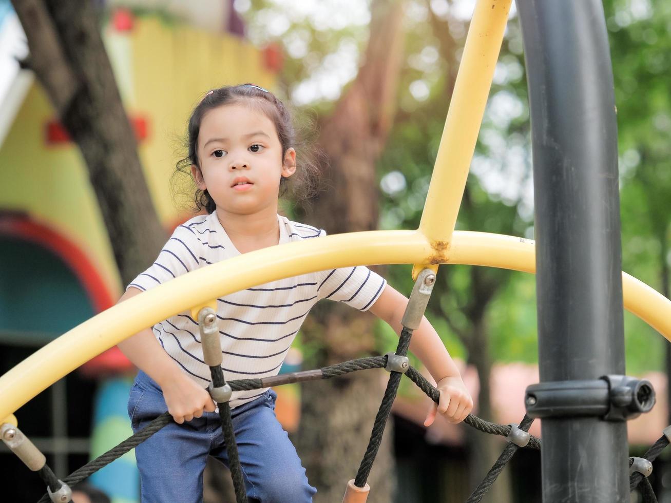 Young Asian girls are having fun clambering on rope nets in a playground photo