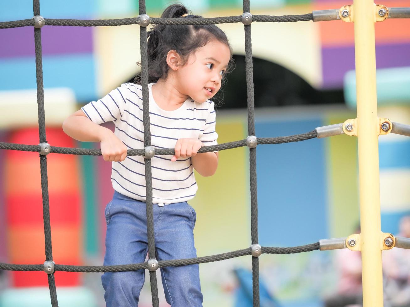 Young Asian girls are having fun clambering on rope nets in a playground photo