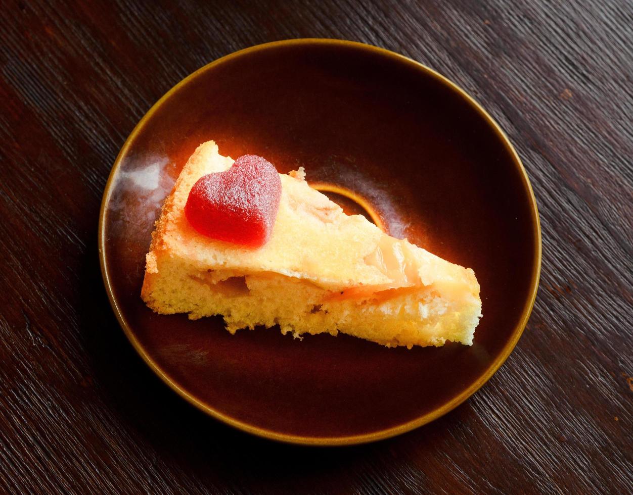 One slice of Apple pie with a marmalade love heart on top on a plate. photo