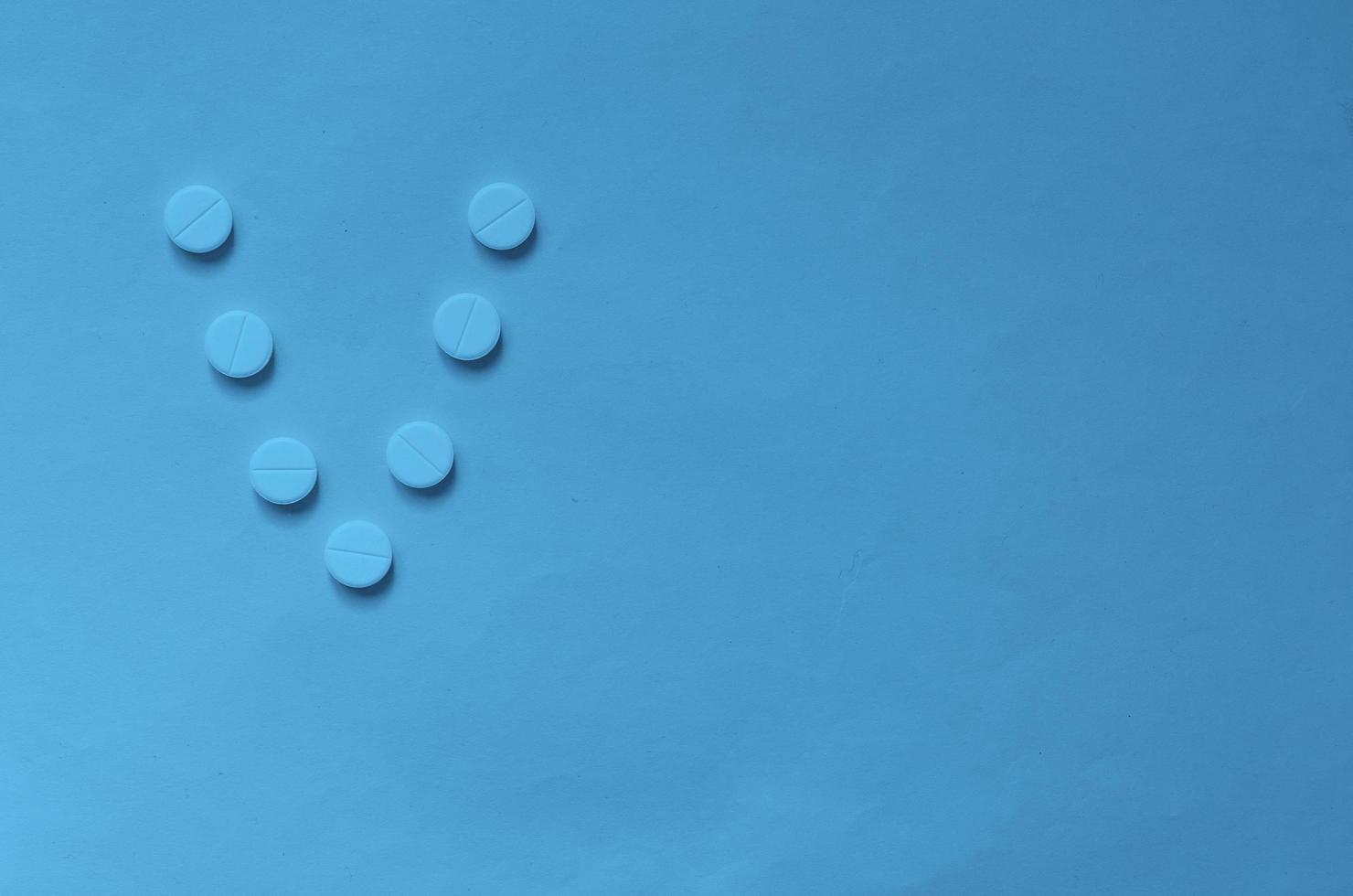 The letter V in the form of pills on classic blue background. photo