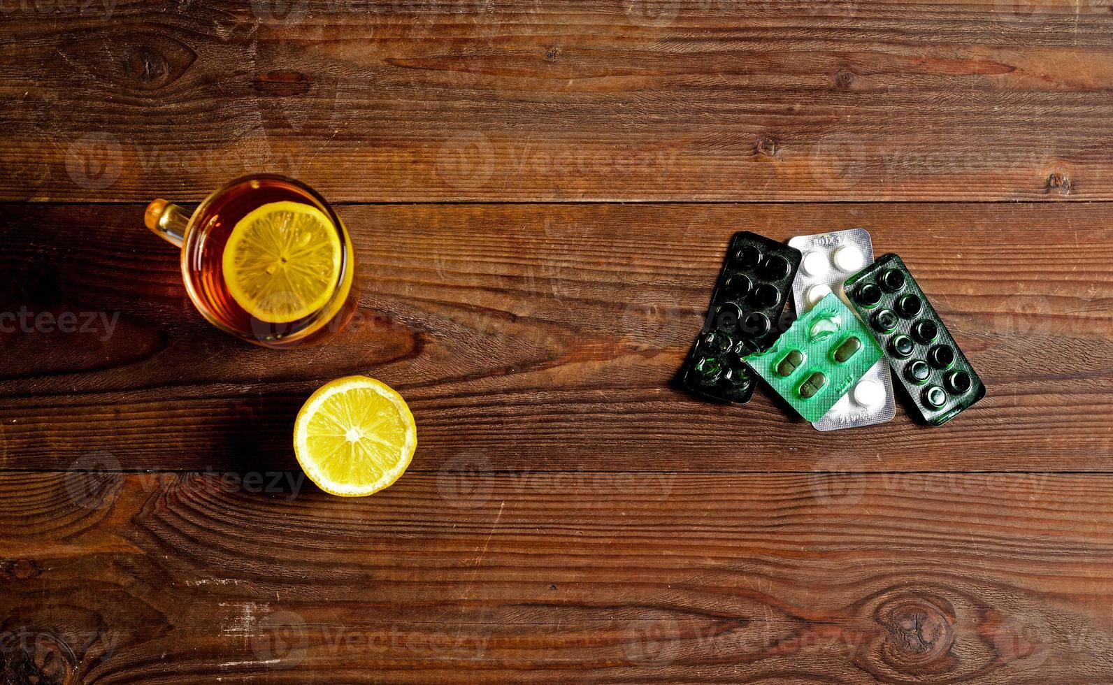 una bebida caliente para un resfriado. otoño. enfermedad. salud. una taza de té con dos trozos de limón y pastillas para el resfriado. foto