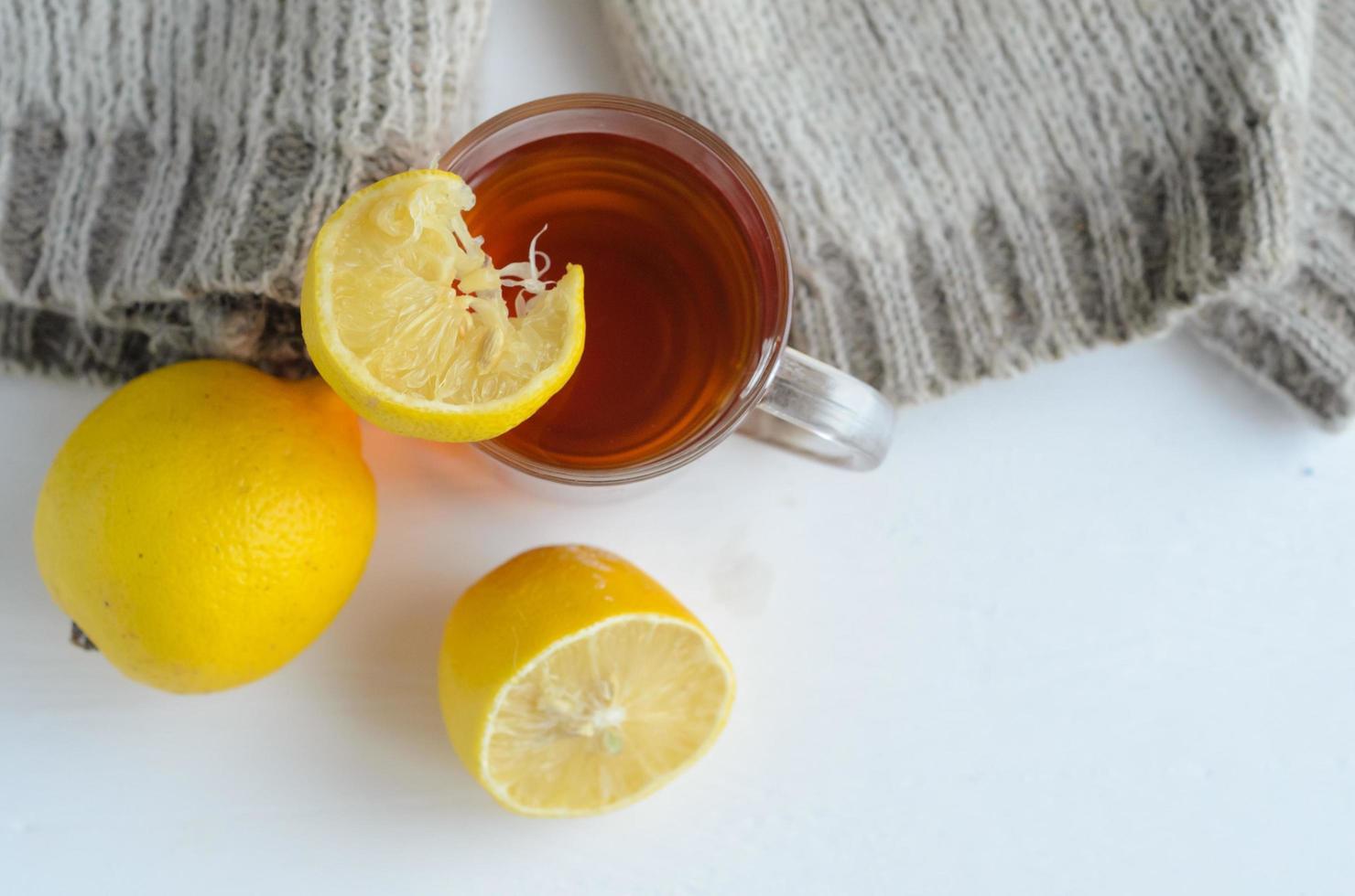 taza de té con limón, un limón y medio y suéter de lana. foto