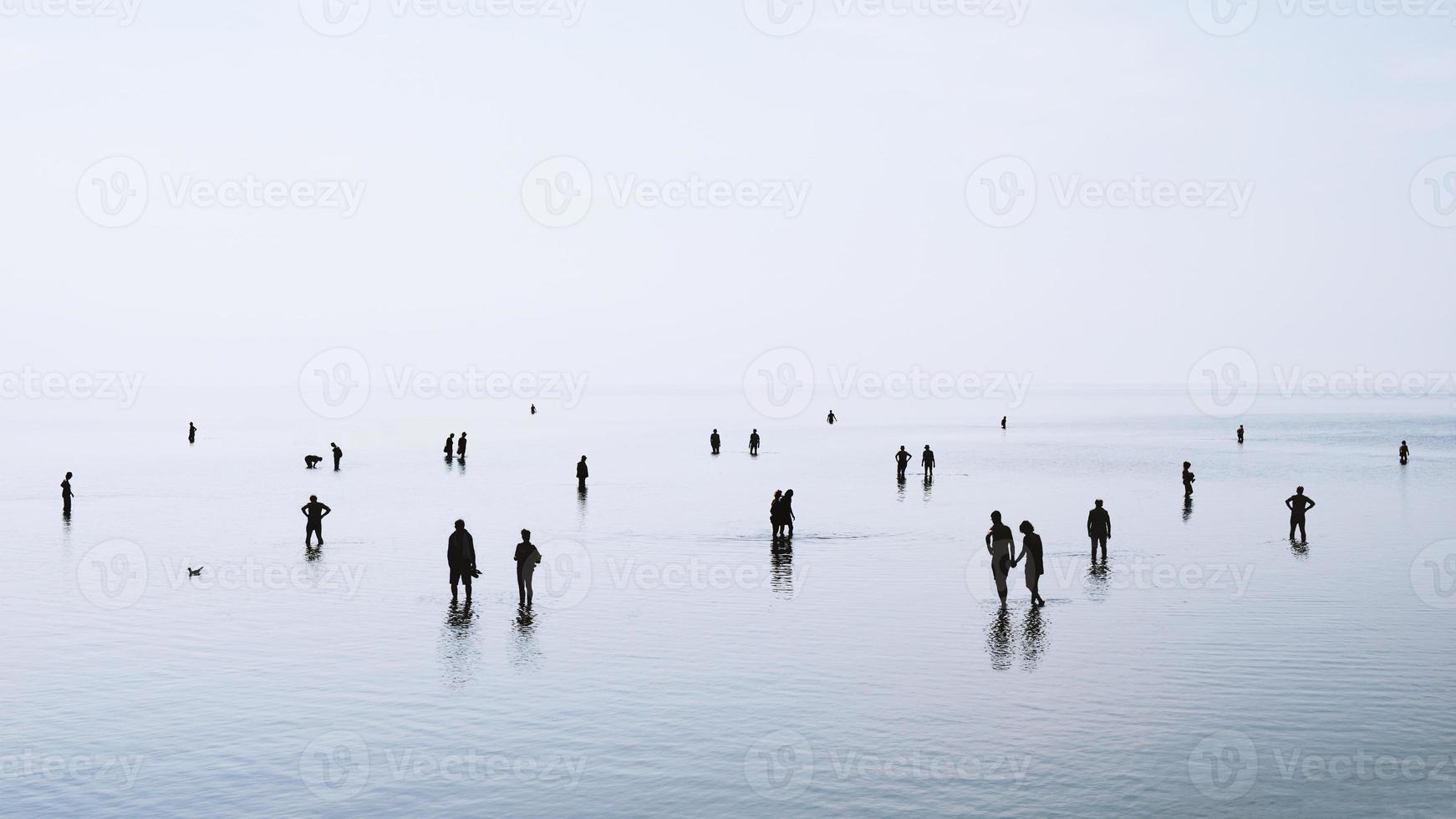 siluetas de personas caminando y nadando en aguas poco profundas foto