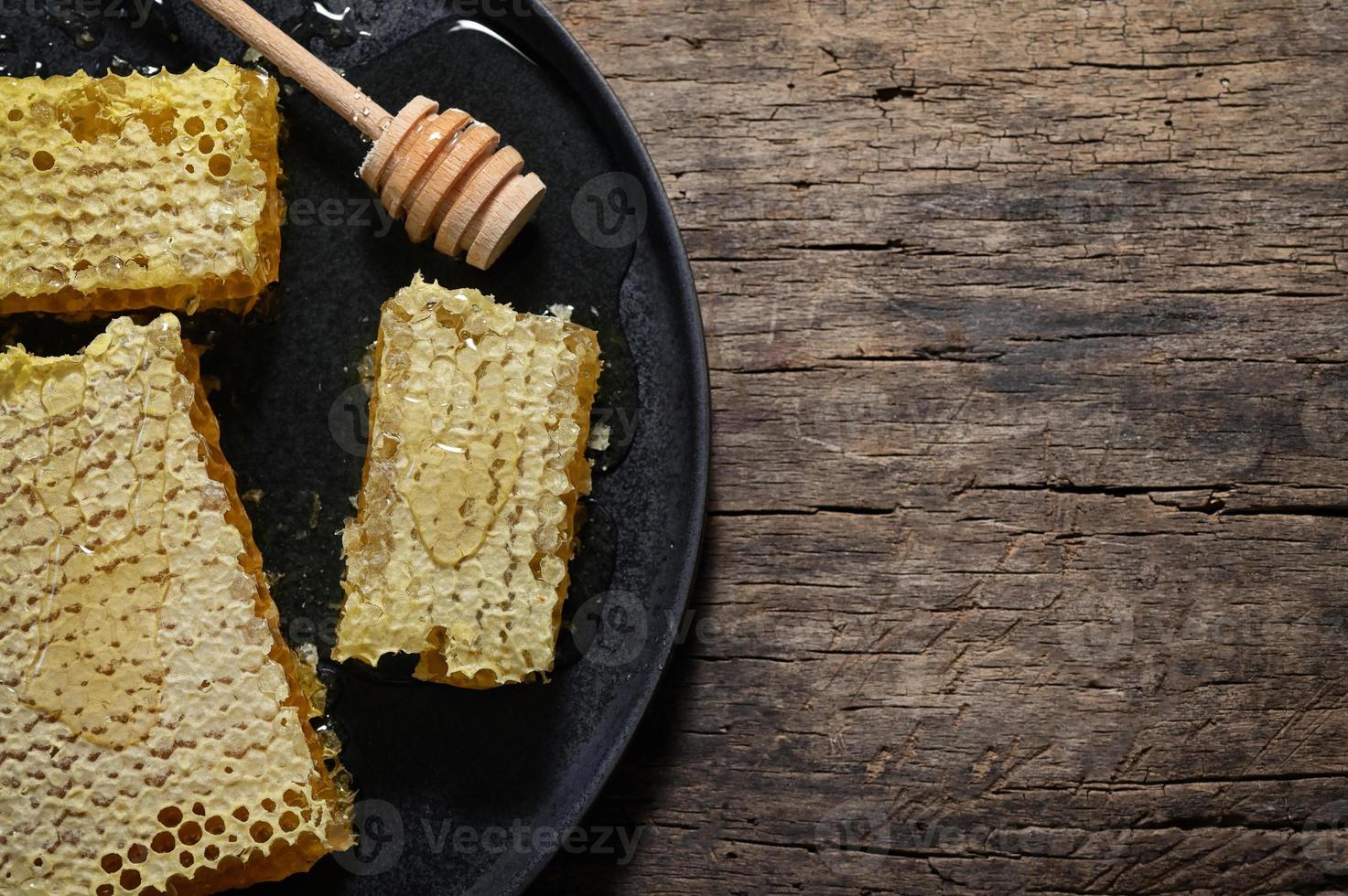 cucharón de panal y miel sobre mesa de madera foto