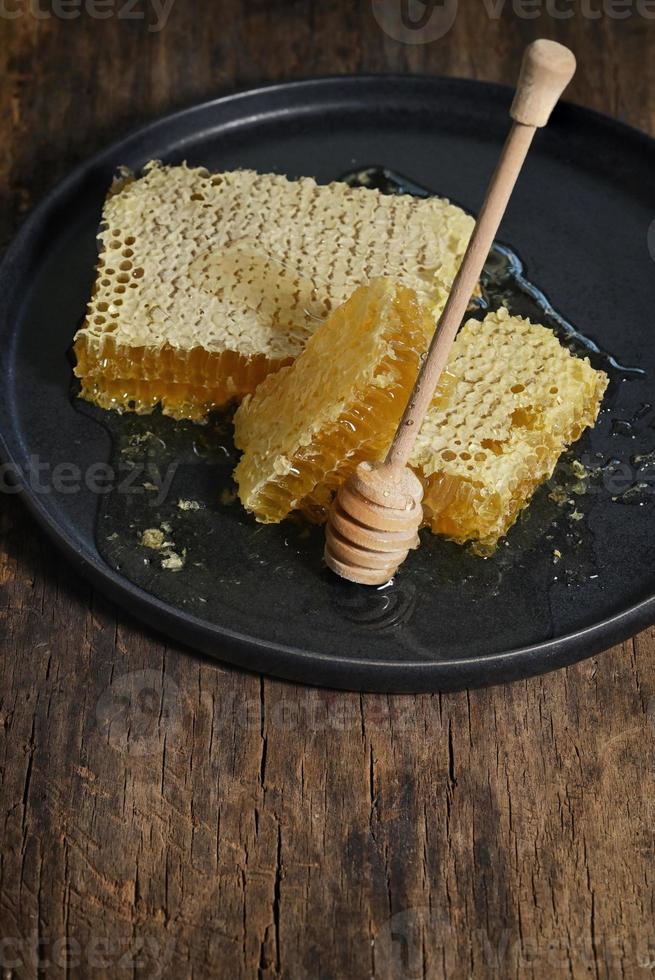 cucharón de panal y miel sobre mesa de madera foto