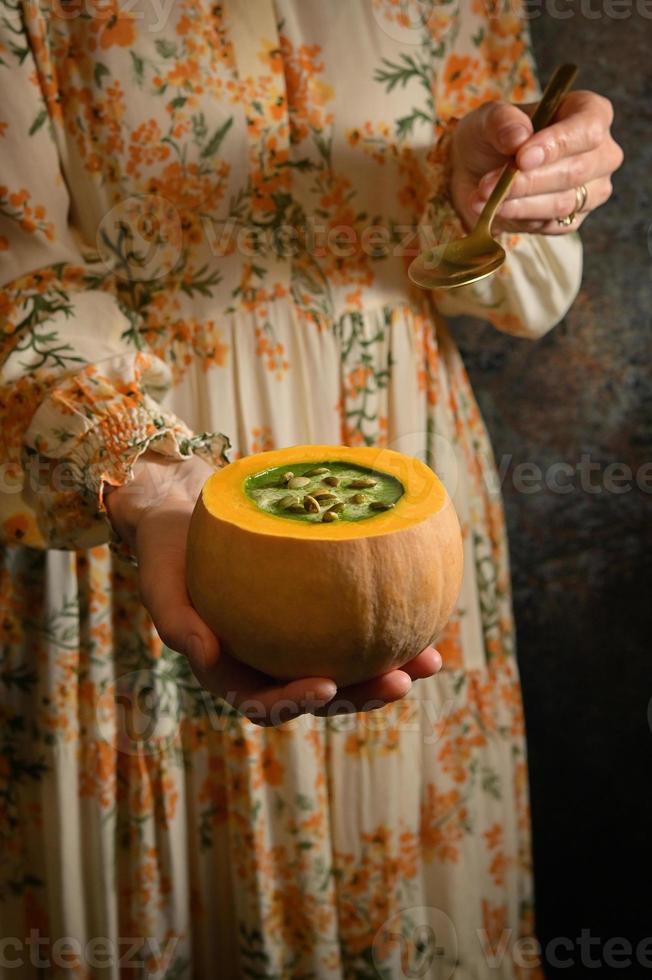 mujer sosteniendo sopa de crema de calabaza saludable foto