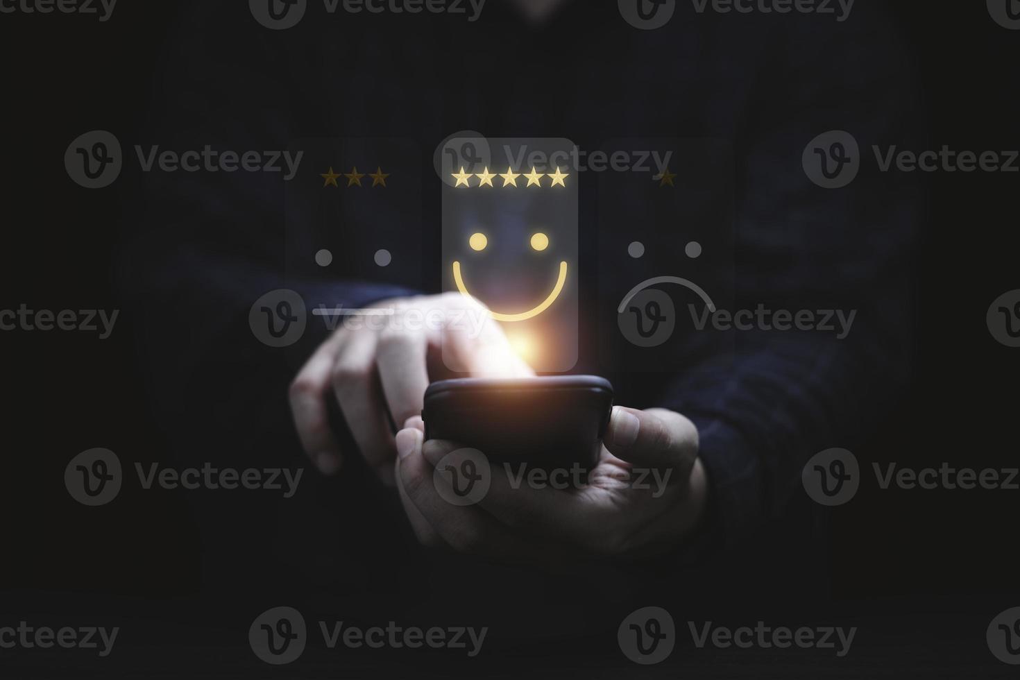 Businessman using smartphone for select smiley face icon for client evaluation and customer satisfaction after use product and service concept. photo