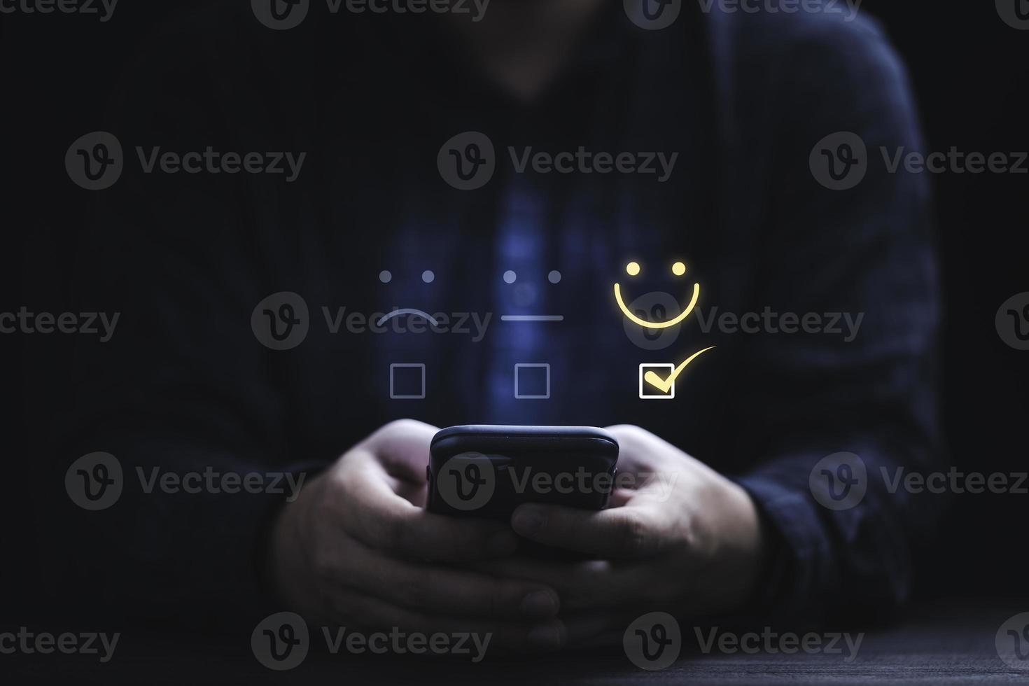 Businessman using smartphone for select smiley face icon for client evaluation and customer satisfaction after use product and service concept. photo