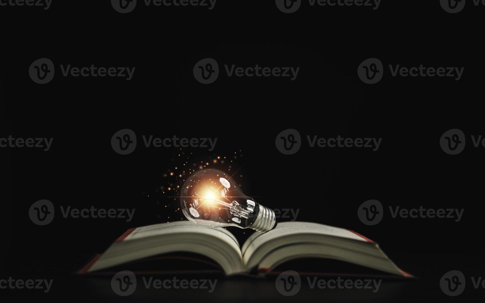 Lightbulb glowing on book over dark background for creative thinking idea after reading and study concept. photo